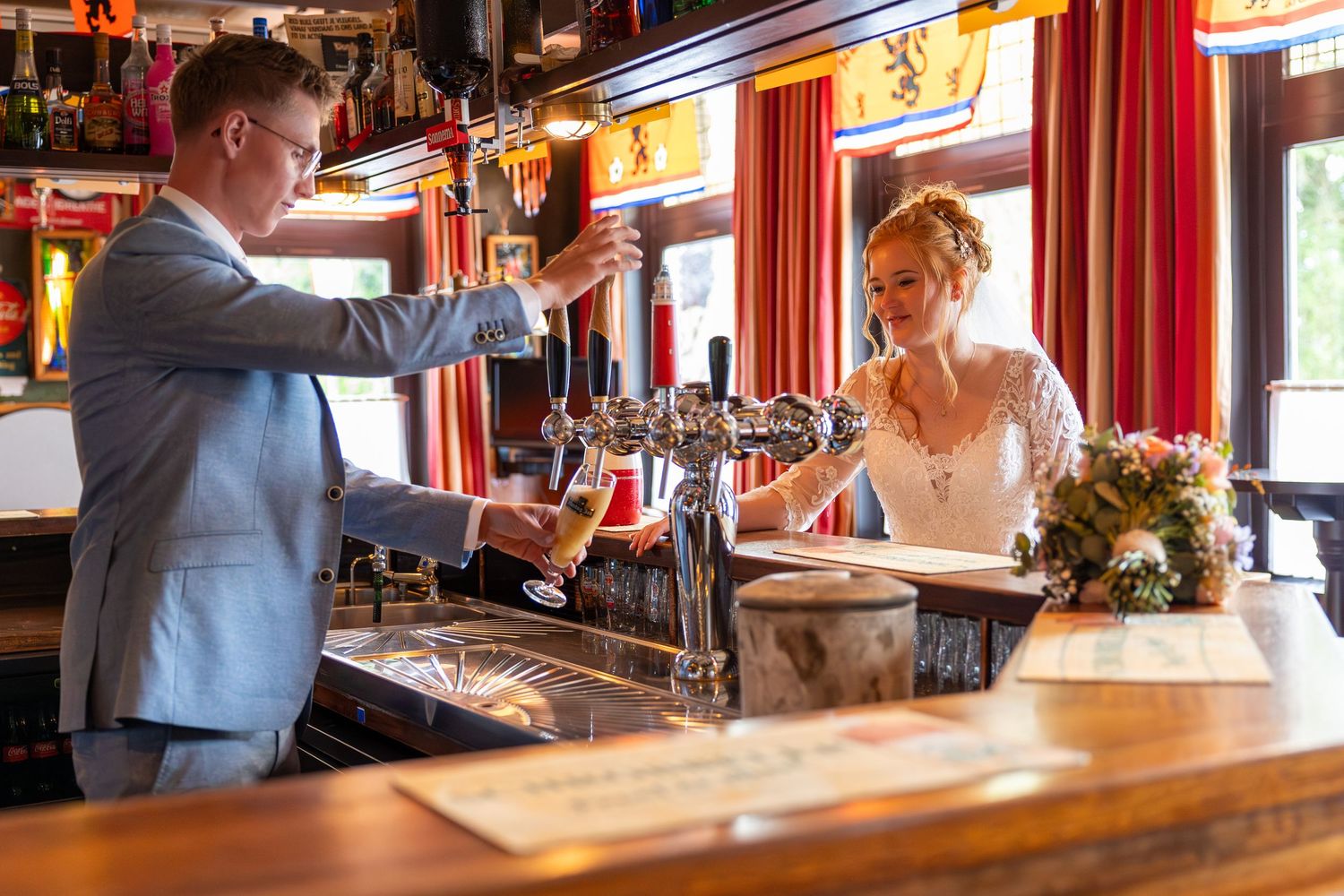 A couple in formal wear interacts across a bar counter with beer taps.
