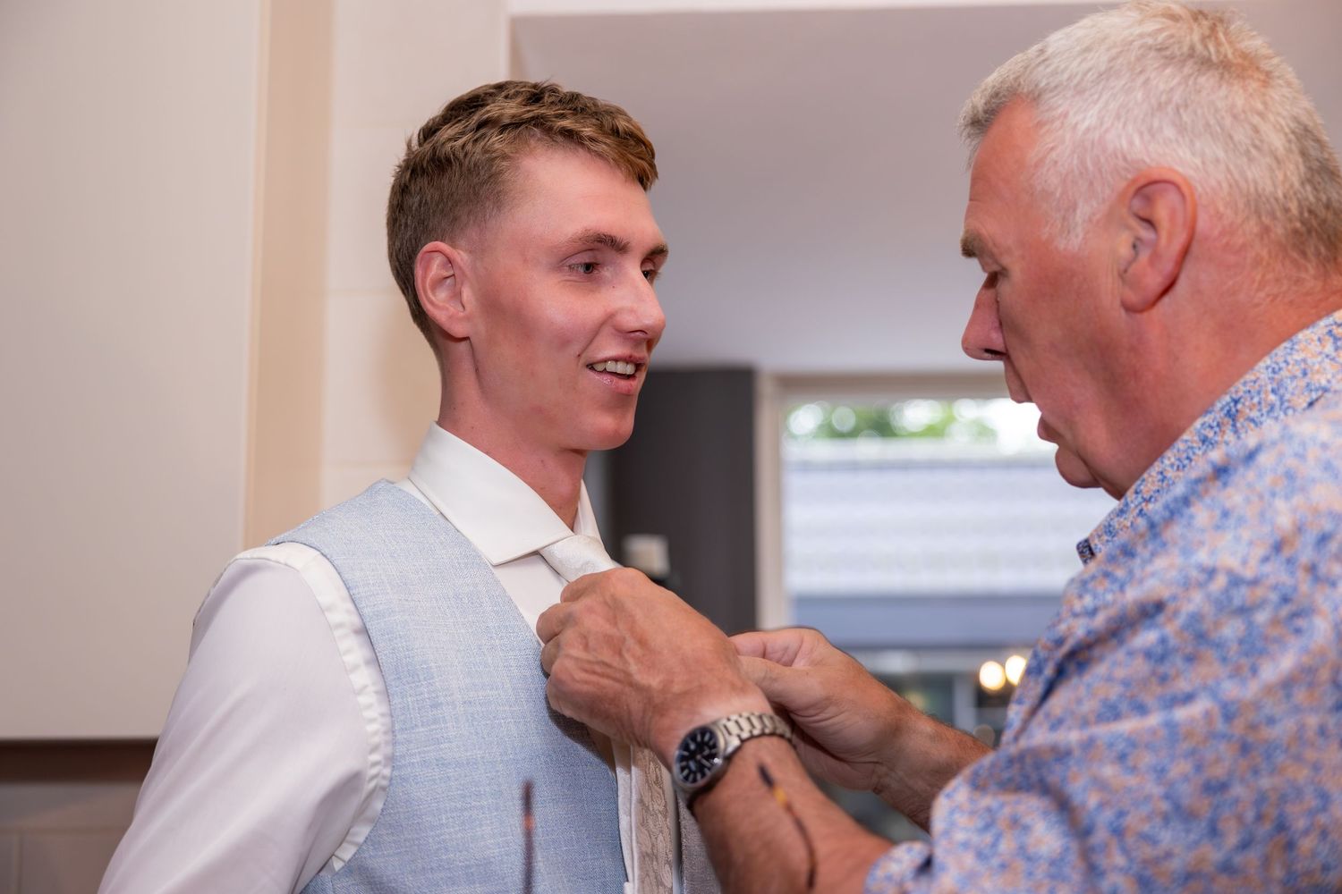 Person having vest adjusted during formal dressing preparation.