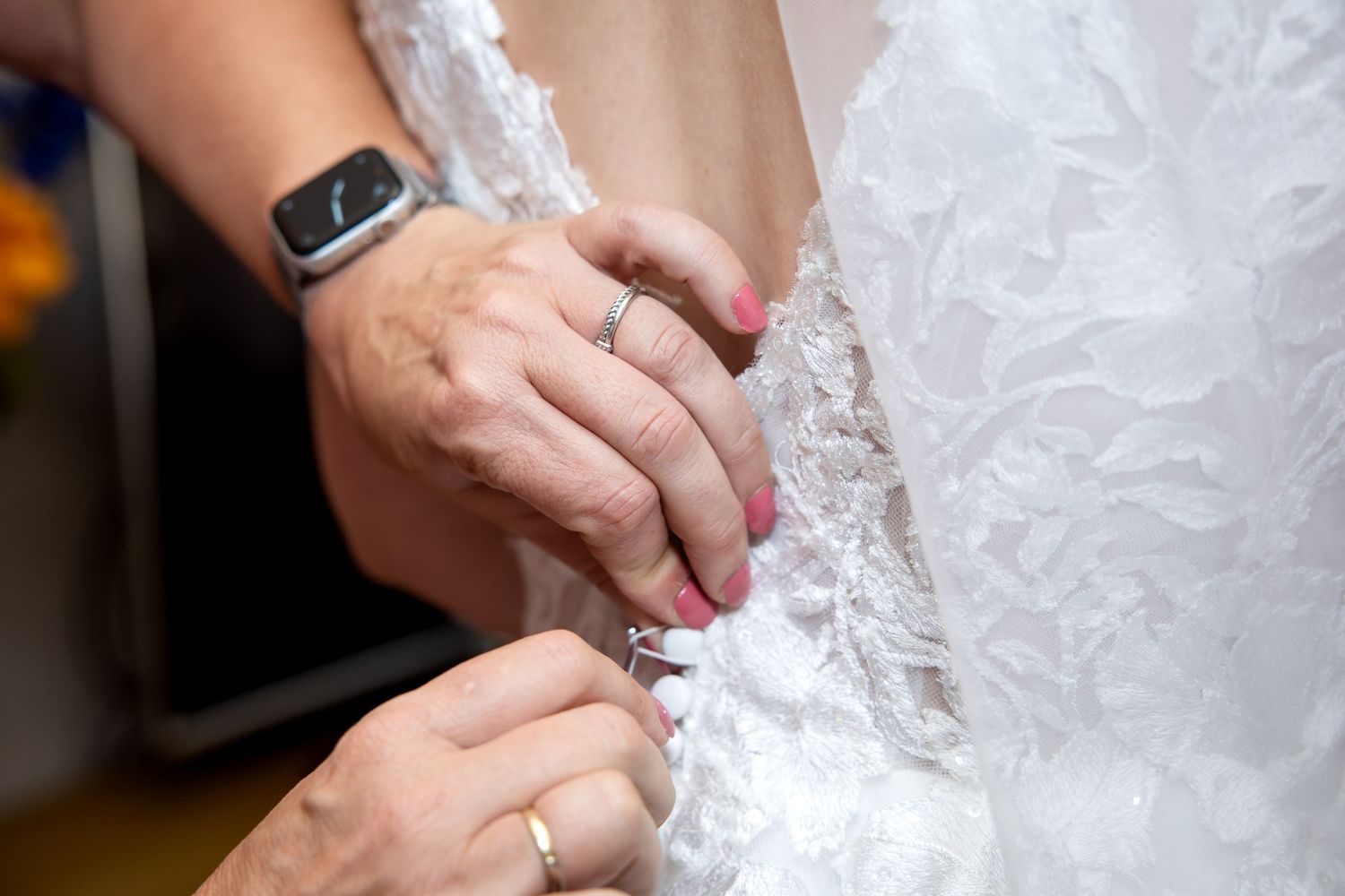 Close-up van handen die de trouwjurk sluiten, dicht doen
