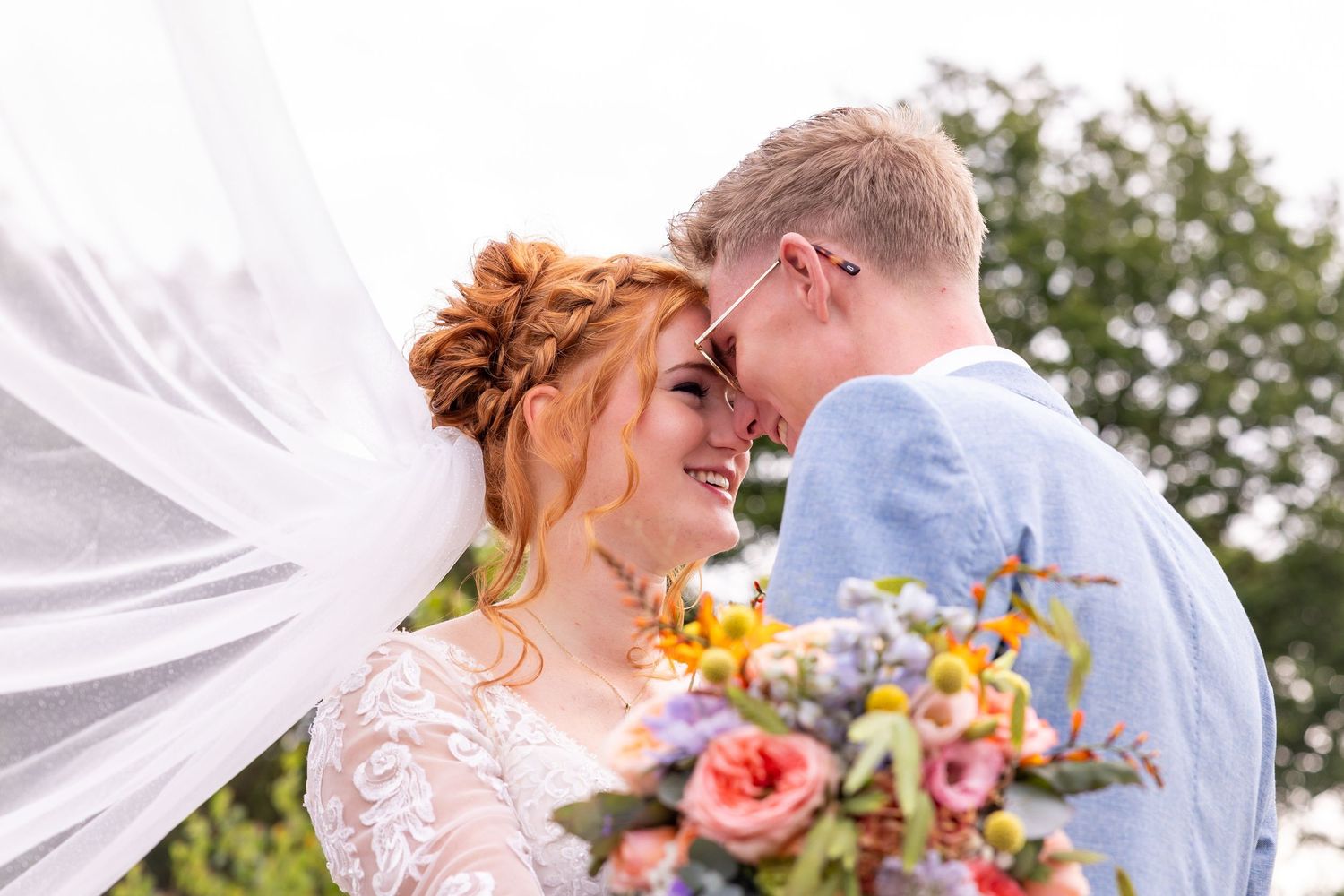 A romantic wedding moment with flowing veil and colorful bouquet.