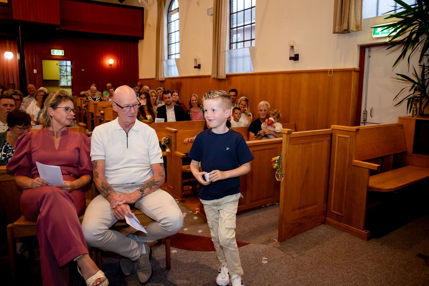Mensen verzamelden zich in houten banken in een kerk met warme verlichting en hoge ramen.