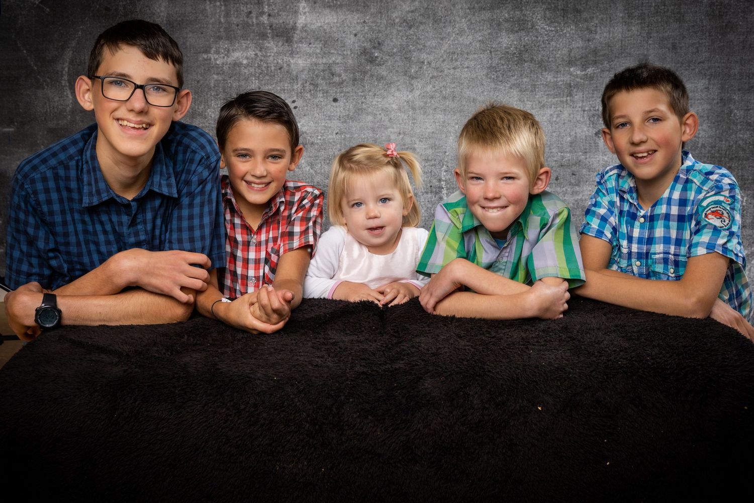 A series of black and white family portraits showing siblings arranged in different poses against a textured background.