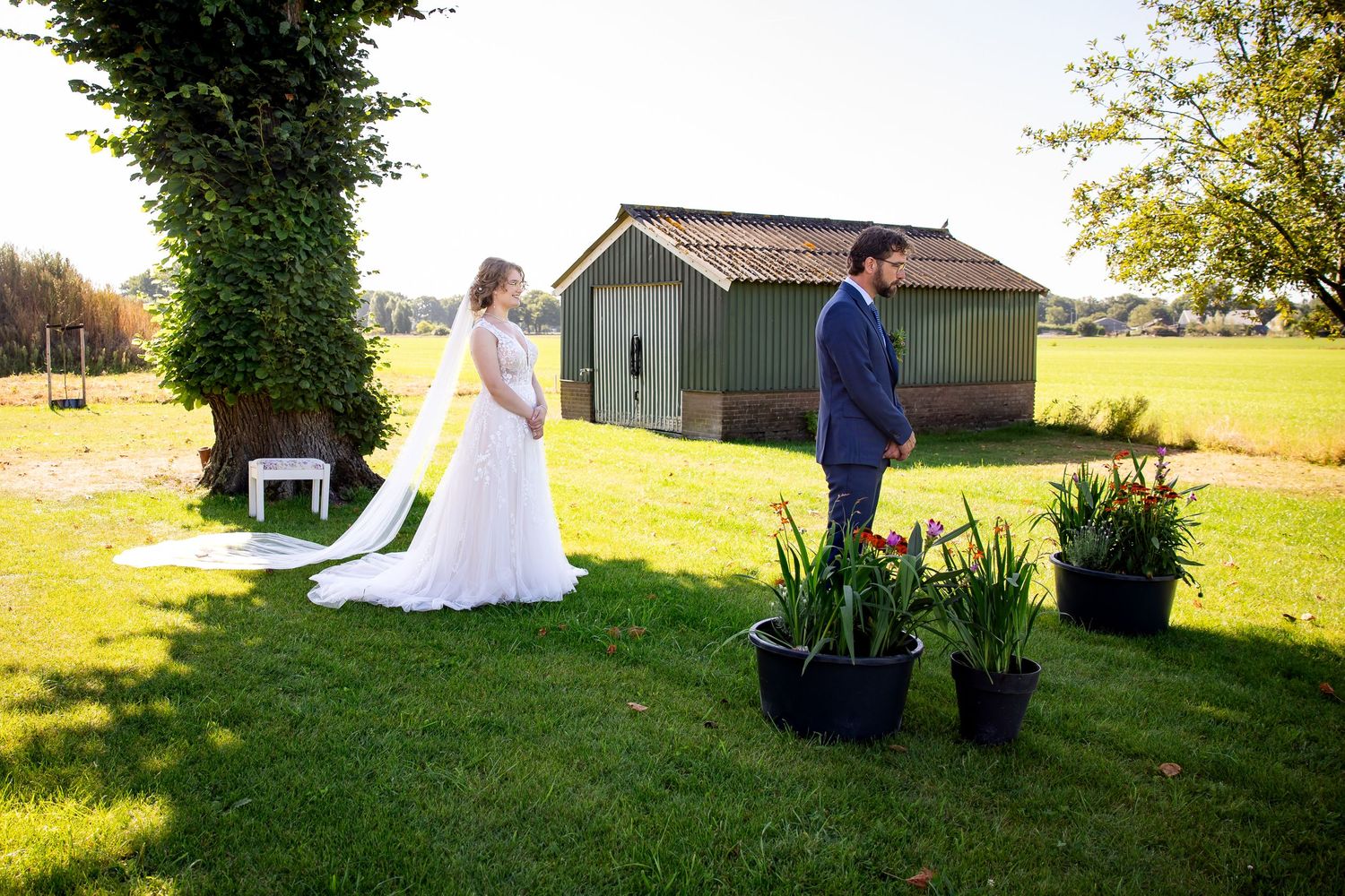 Romantic first look scene between couple on sunny lawn with brick house backdrop.