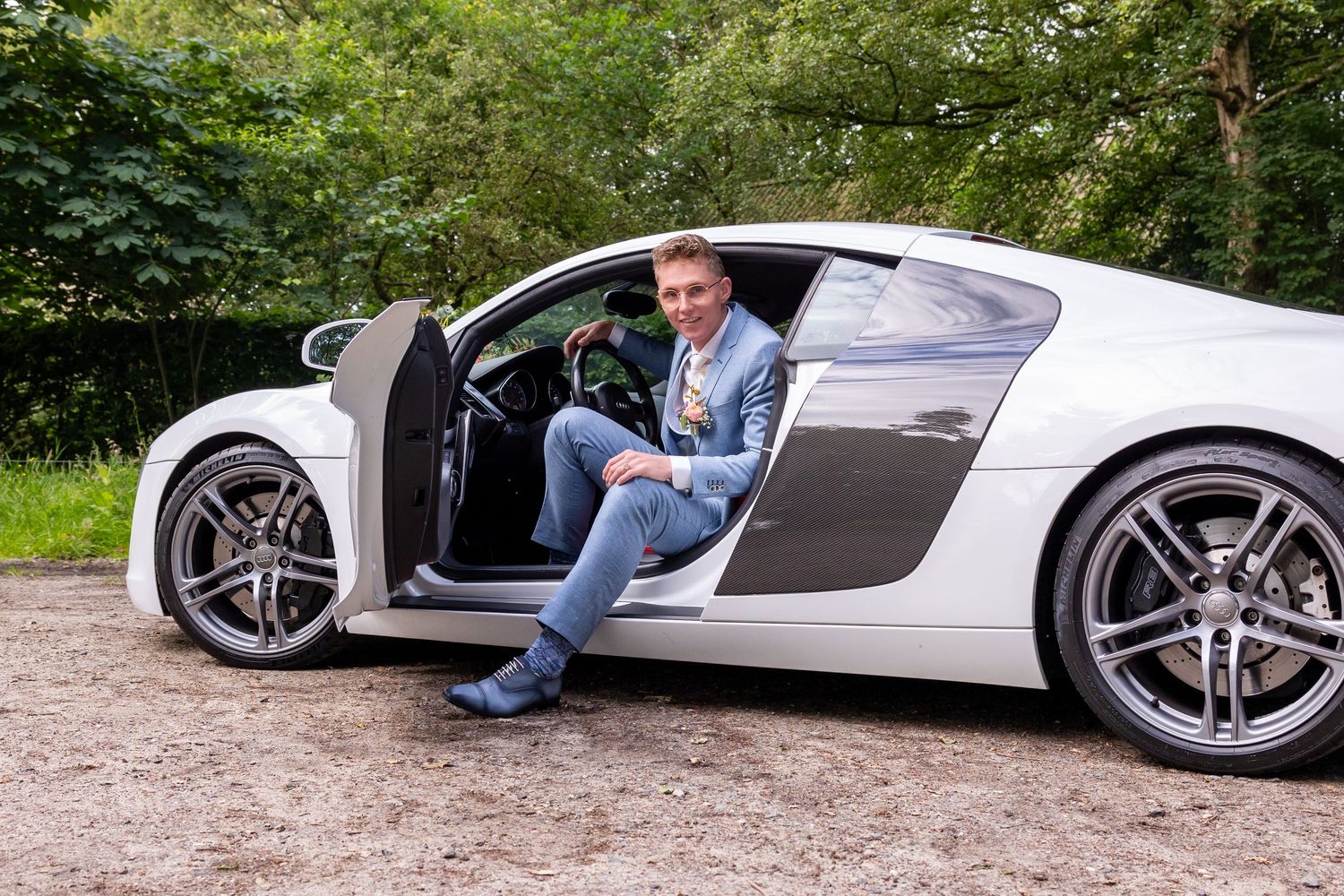 White Audi R8 supercar showcased from multiple angles on gravel path.