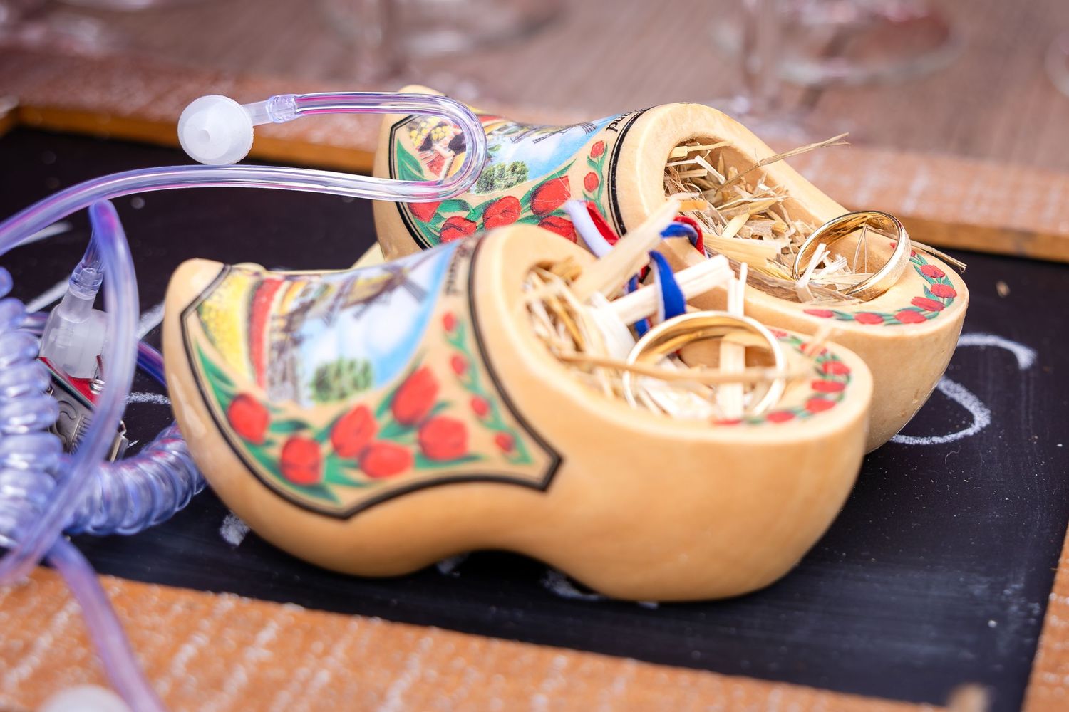 Colorfully decorated wooden clogs displayed on dark wooden surface.