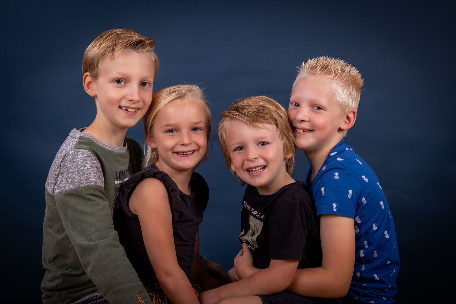 Group portrait of children posing together against dark blue background in casual attire.