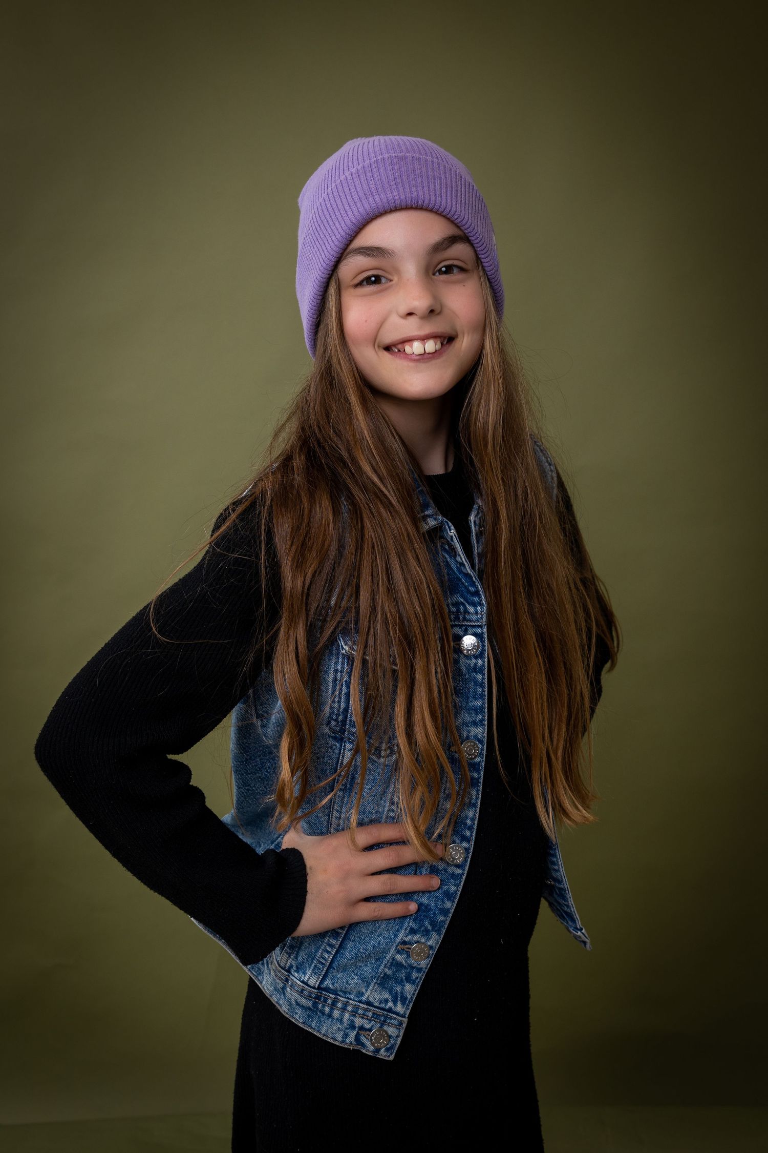 A series of expressive portraits showing a person in a denim jacket, black sweater and purple beanie against a dark background.