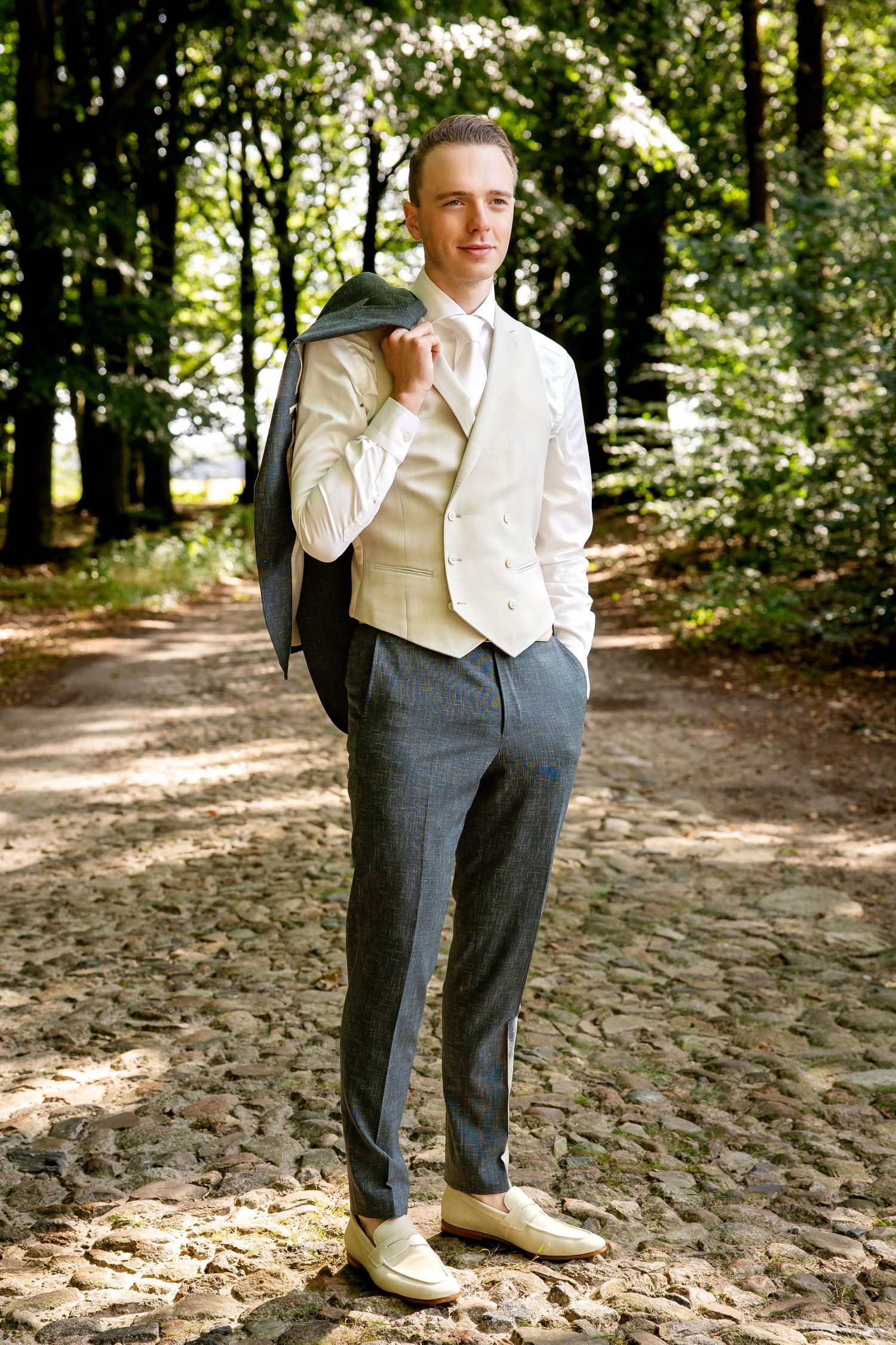Details van bruidegom: en grijze pantalon en een wit overhemd in natuurlijk buitenlicht.