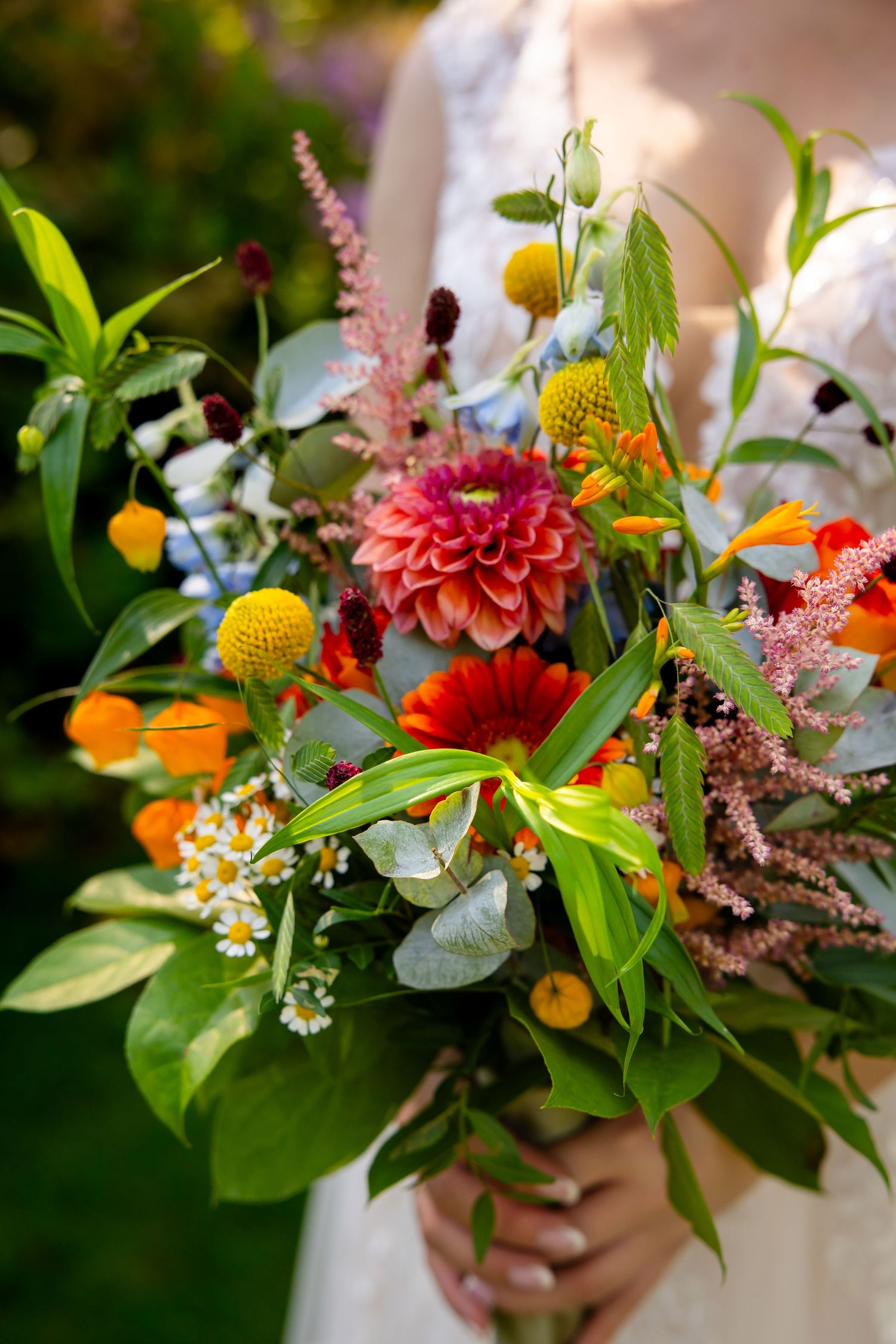A vibrant wedding bouquet features colorful dahlias, wildflowers, and greenery.