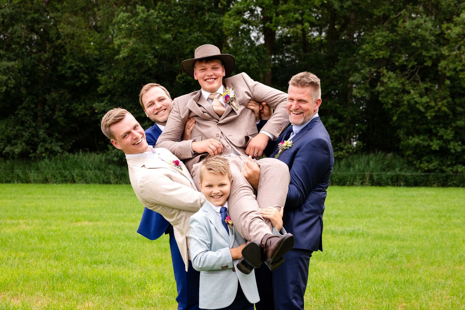 Family playfully poses together on lush green grass during outdoor photo session.