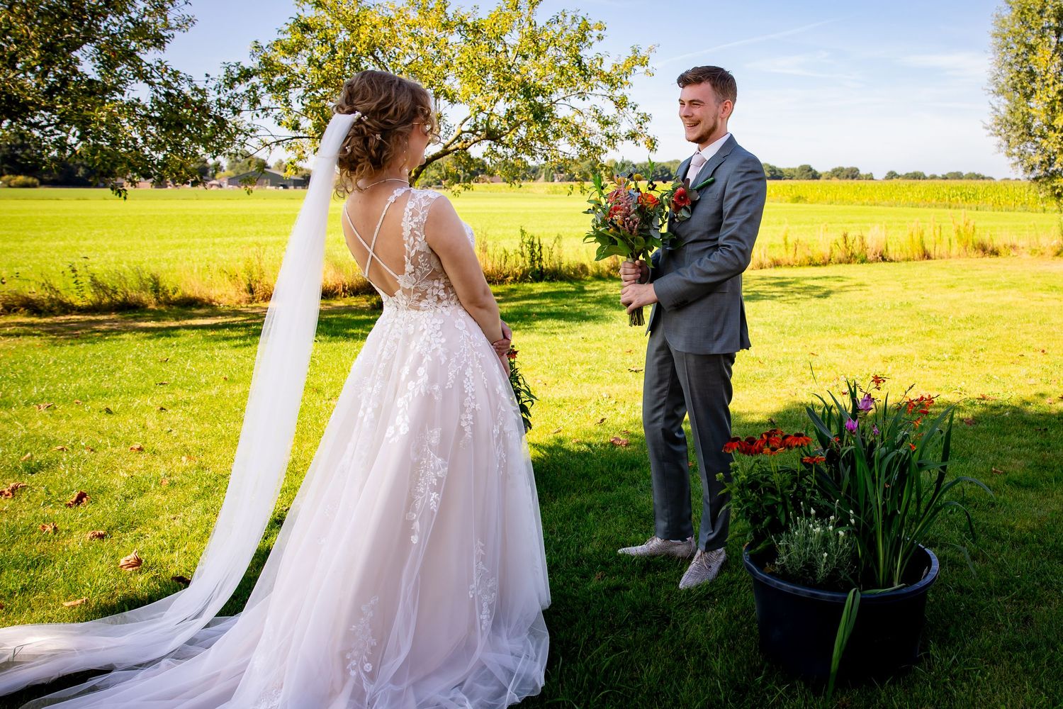 A wedding couple shares a moment in a scenic outdoor setting with vibrant green fields.