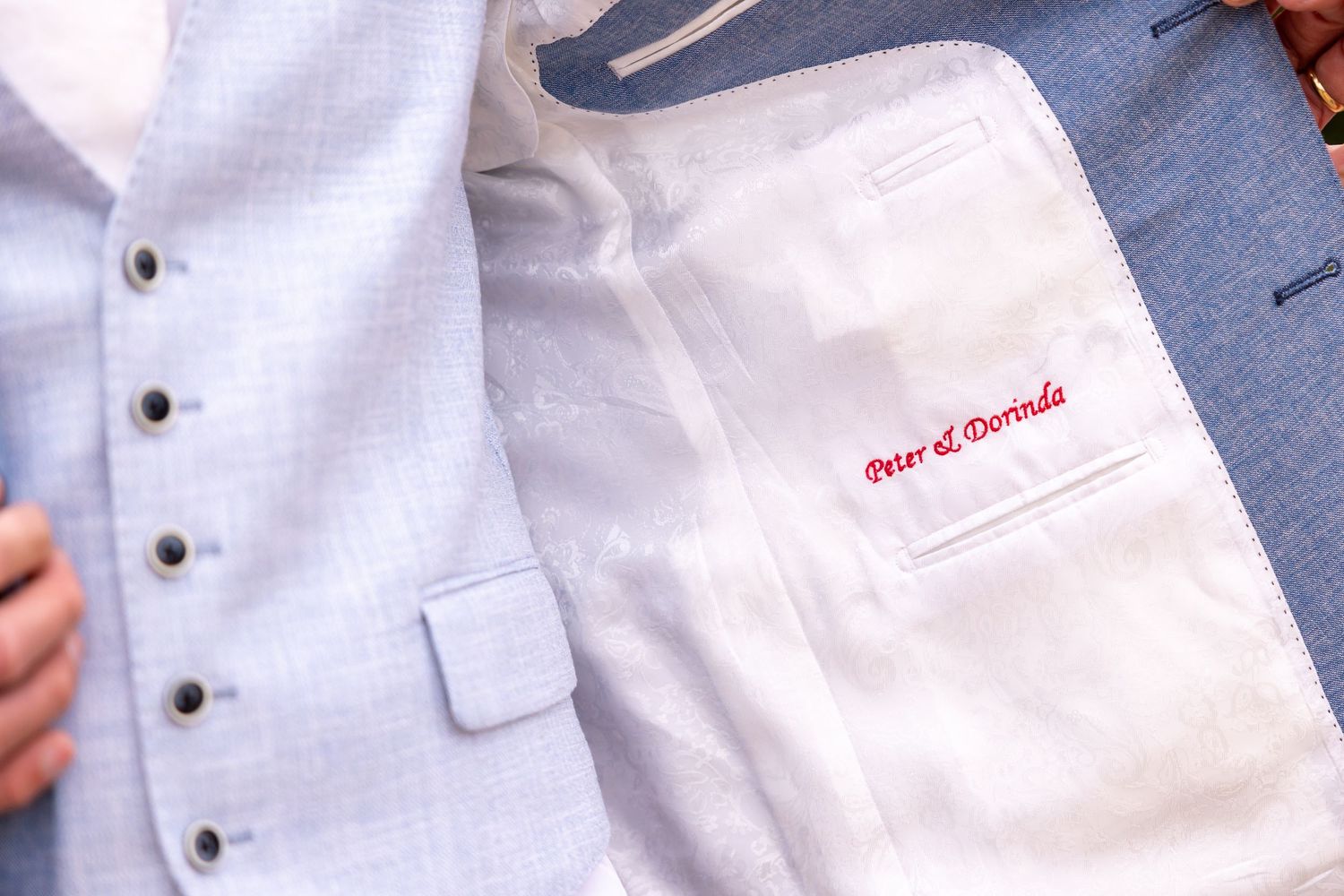 Close-up detail of a white wedding vest with embroidered text.