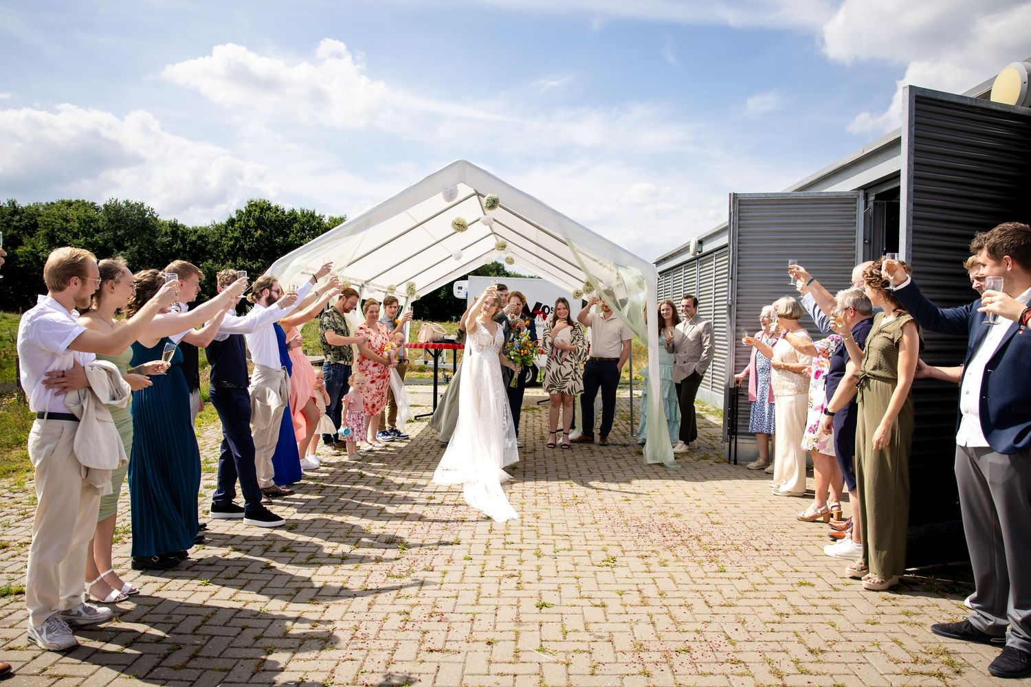 Wedding party lineup on stone path with guests forming celebratory tunnel.