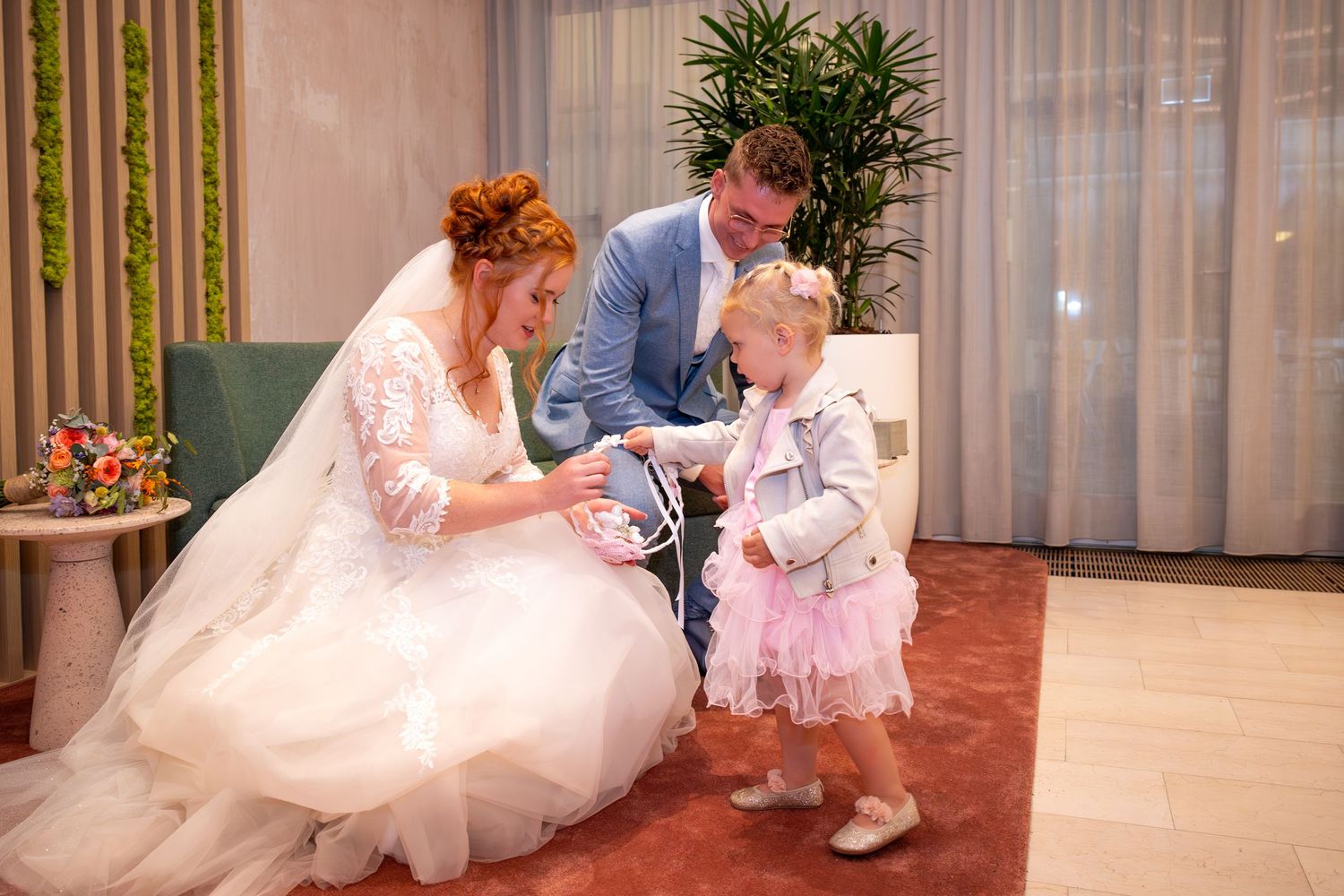 A tender moment between newlyweds and a young flower girl in a pink dress.
