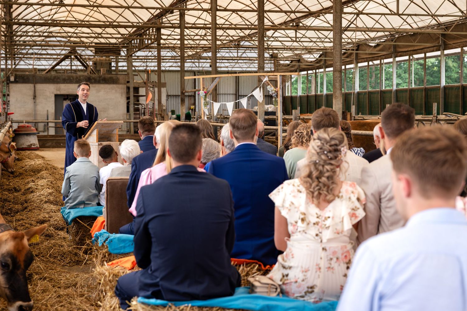 Wedding guests seated in rows inside a rustic barn venue with industrial ceiling.