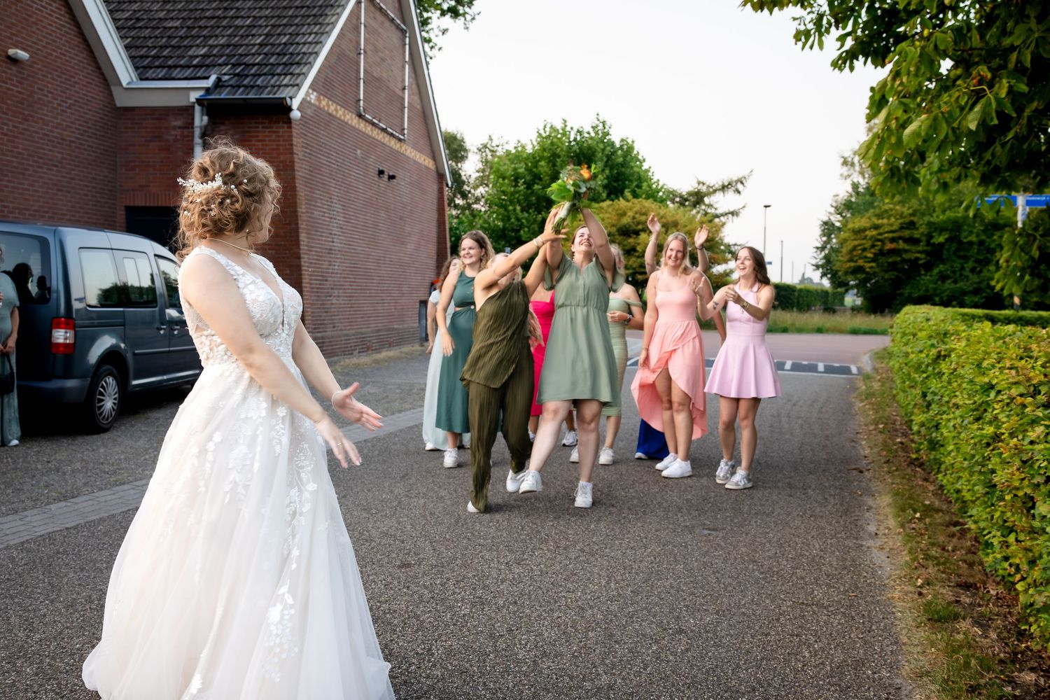Wedding party and guests gather outside a brick building for photos.