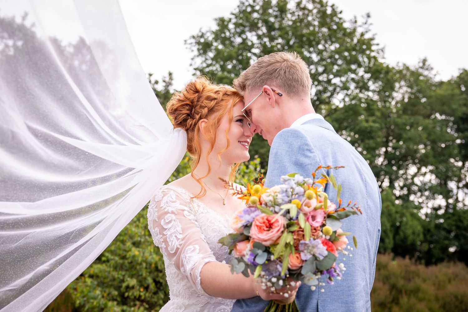 Romantic outdoor wedding photos with sunflowers and flowing white veil against a natural backdrop.