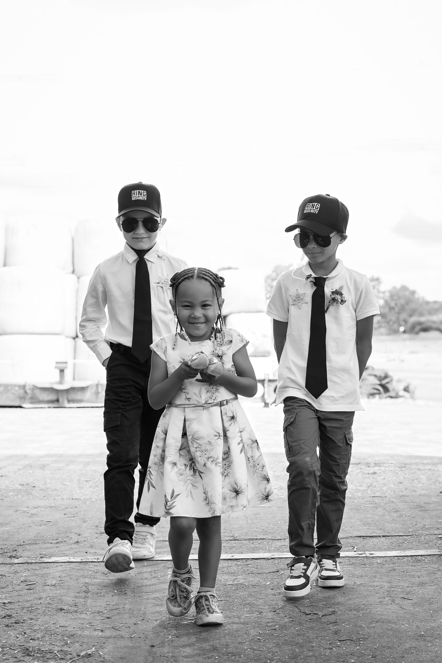 Black and white photo of two children walking together in formal attire with ties.