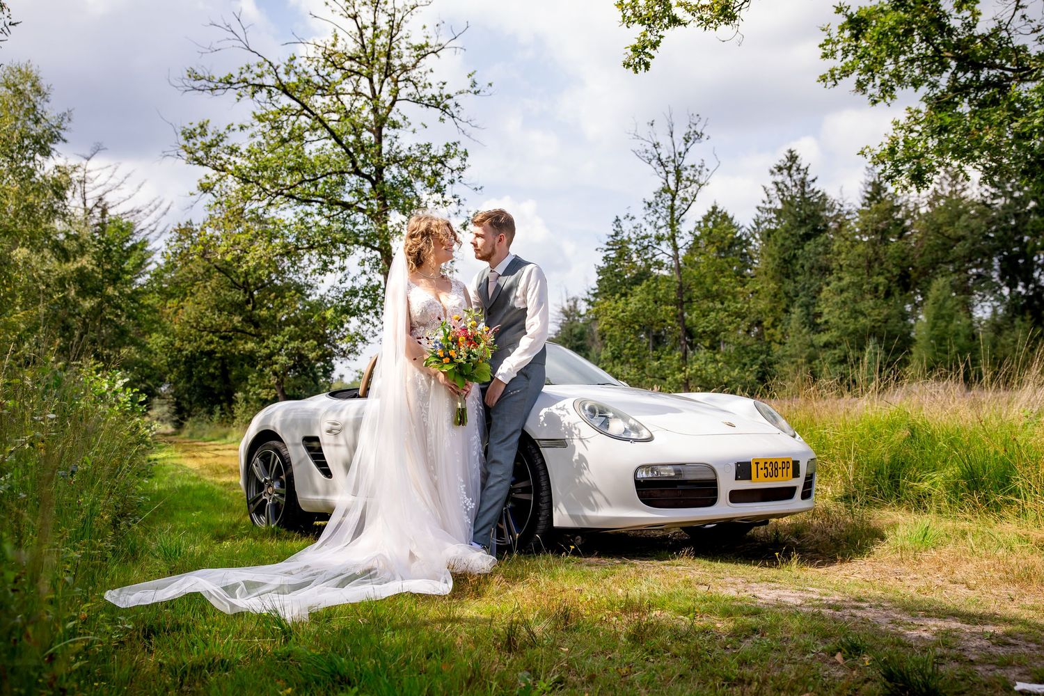 Classic white Porsche sports car parked in scenic outdoor wedding venue.
