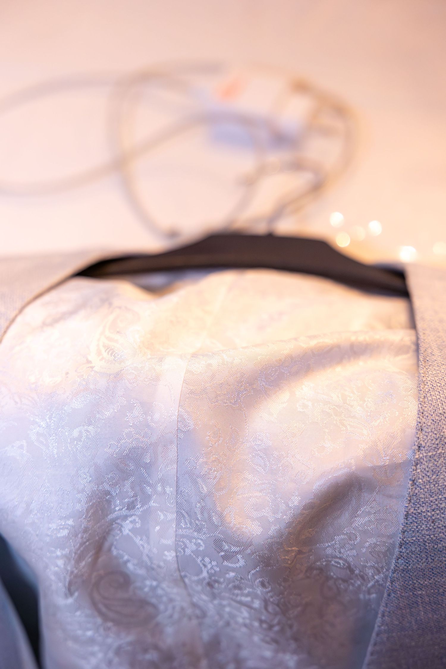 Close-up detail of white lace wedding dress fabric with delicate pattern.