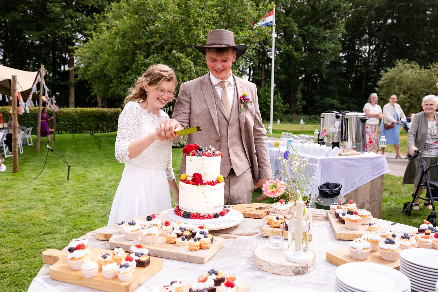Outdoor wedding reception with dessert table setup in a lush garden setting.