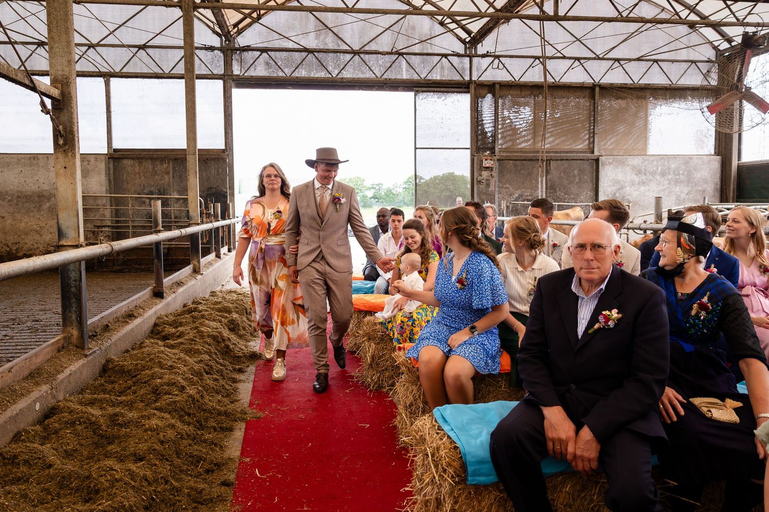Wedding ceremony setup inside a rustic barn with exposed beams and red carpet aisle.