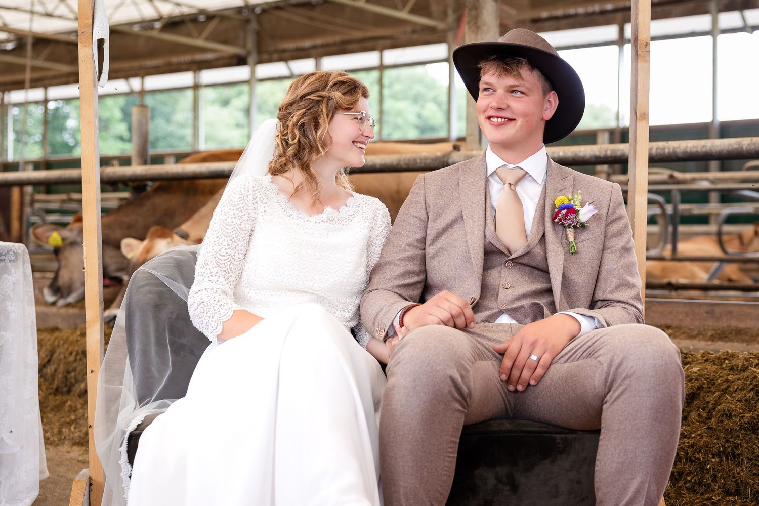 Newlyweds share a joyful moment while seated in a rustic barn setting.