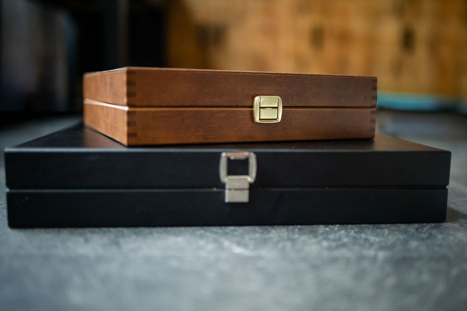 A dark wooden box with brass hardware and hinges shown from multiple angles on a gray surface.