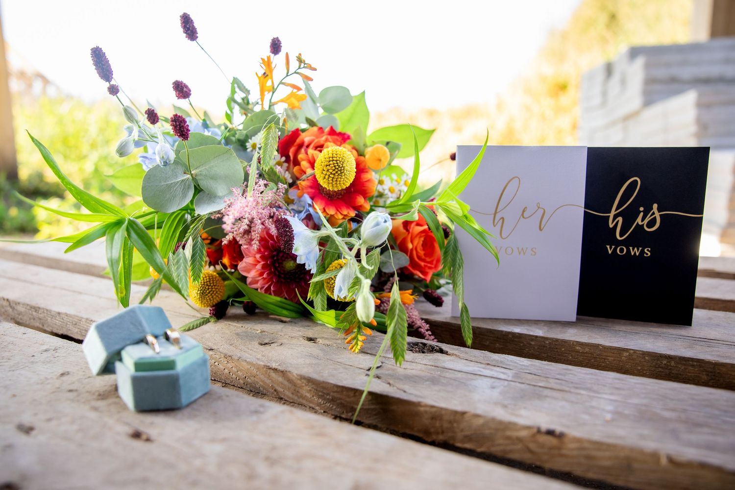 Colorful floral arrangement with place cards on rustic wooden surface.