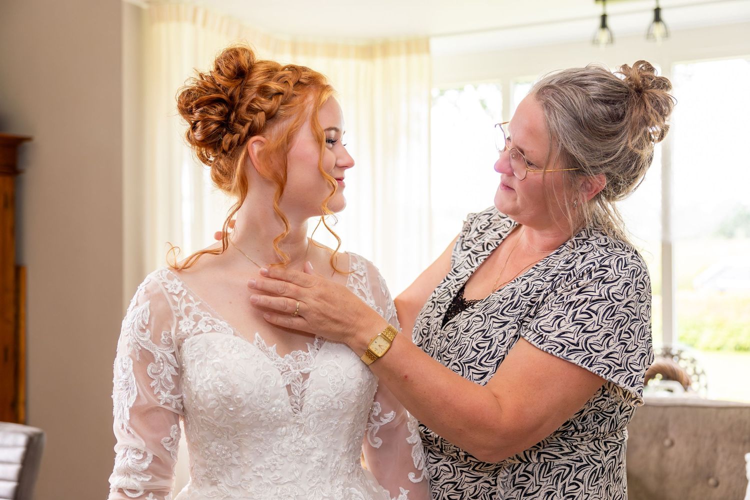Emotional wedding preparation moment in a sunlit room.