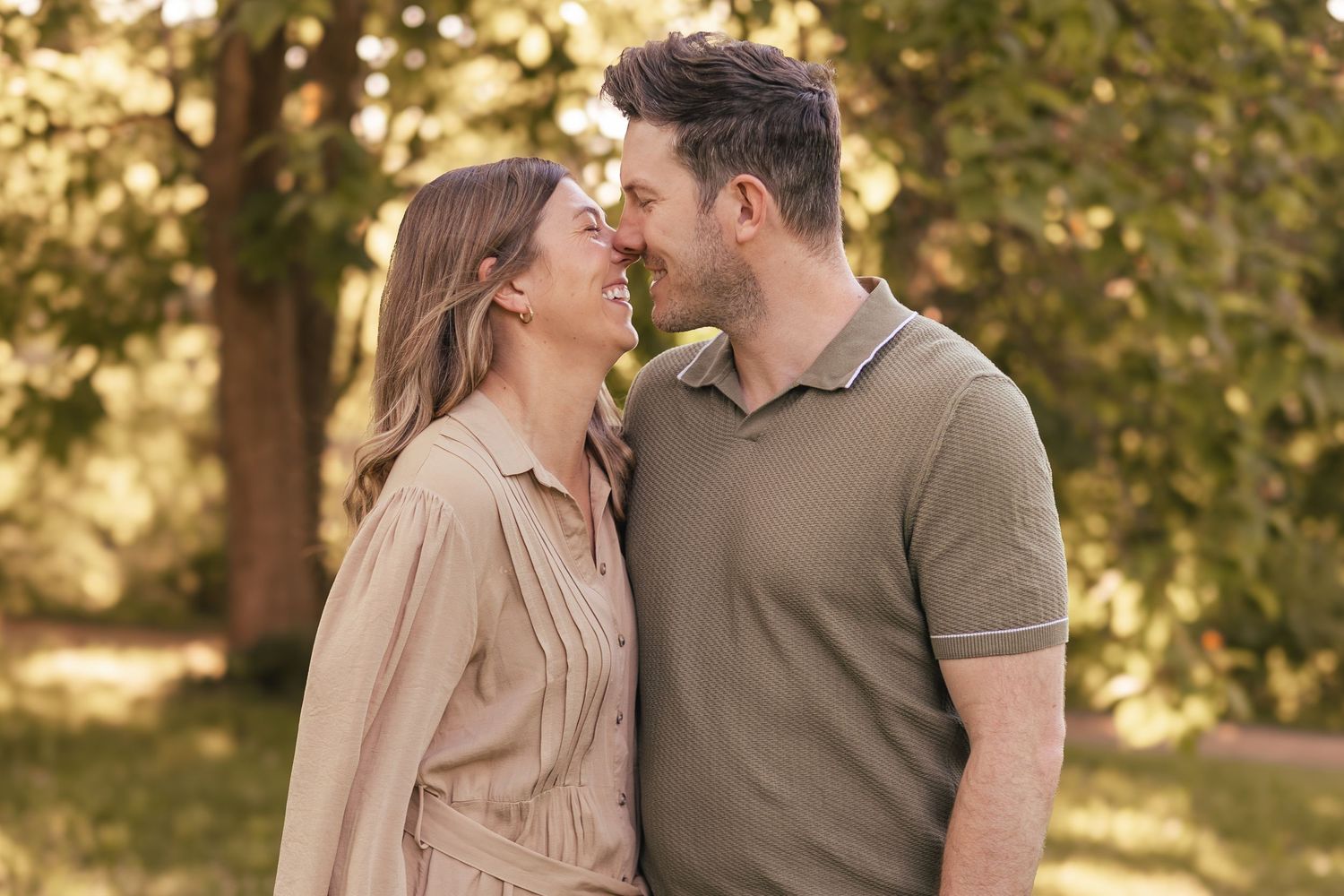 Loving couple sharing a close romantic moment together in a sunny green park.