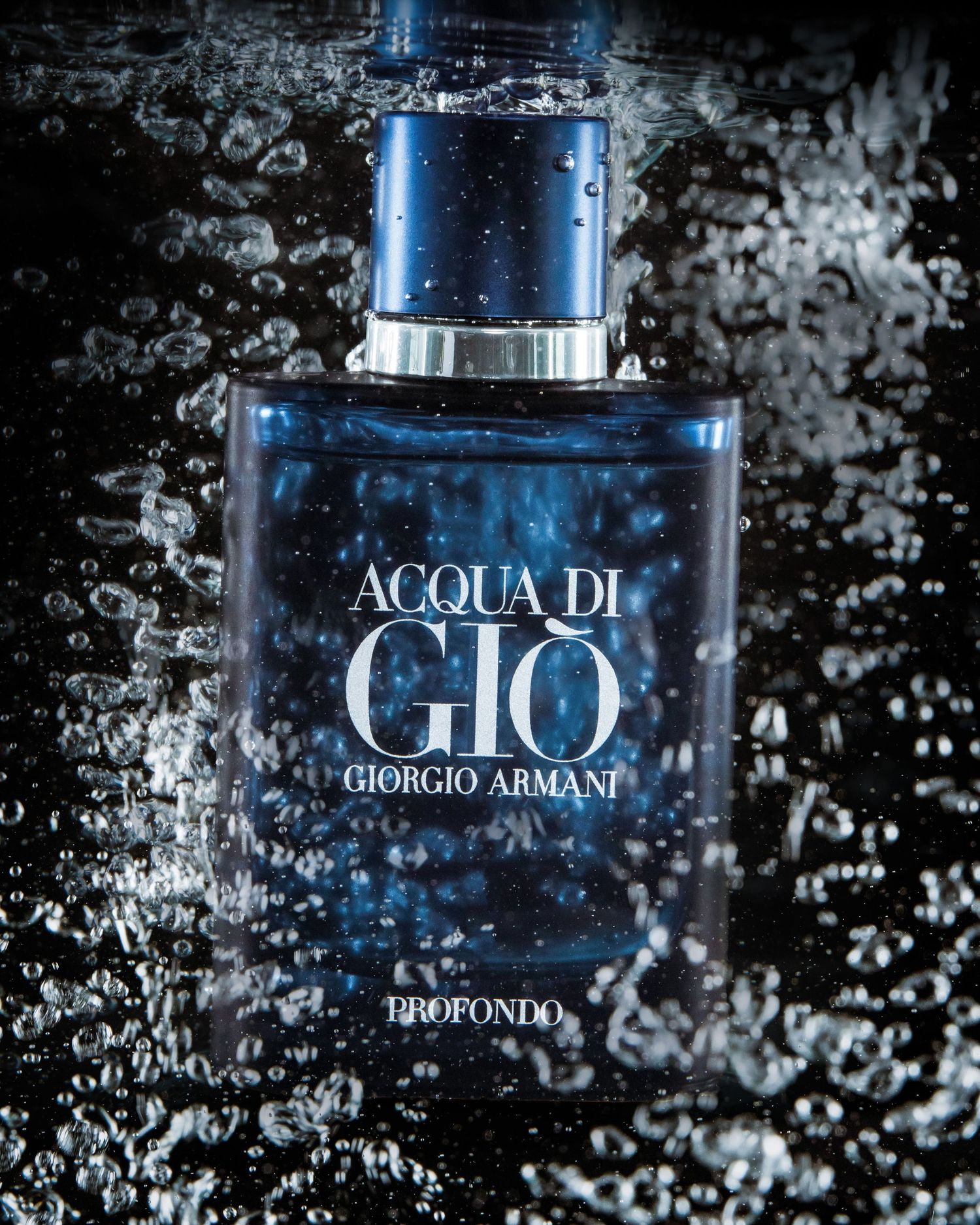 Acqua di Gio perfume bottle surrounded by water splashes on black background.