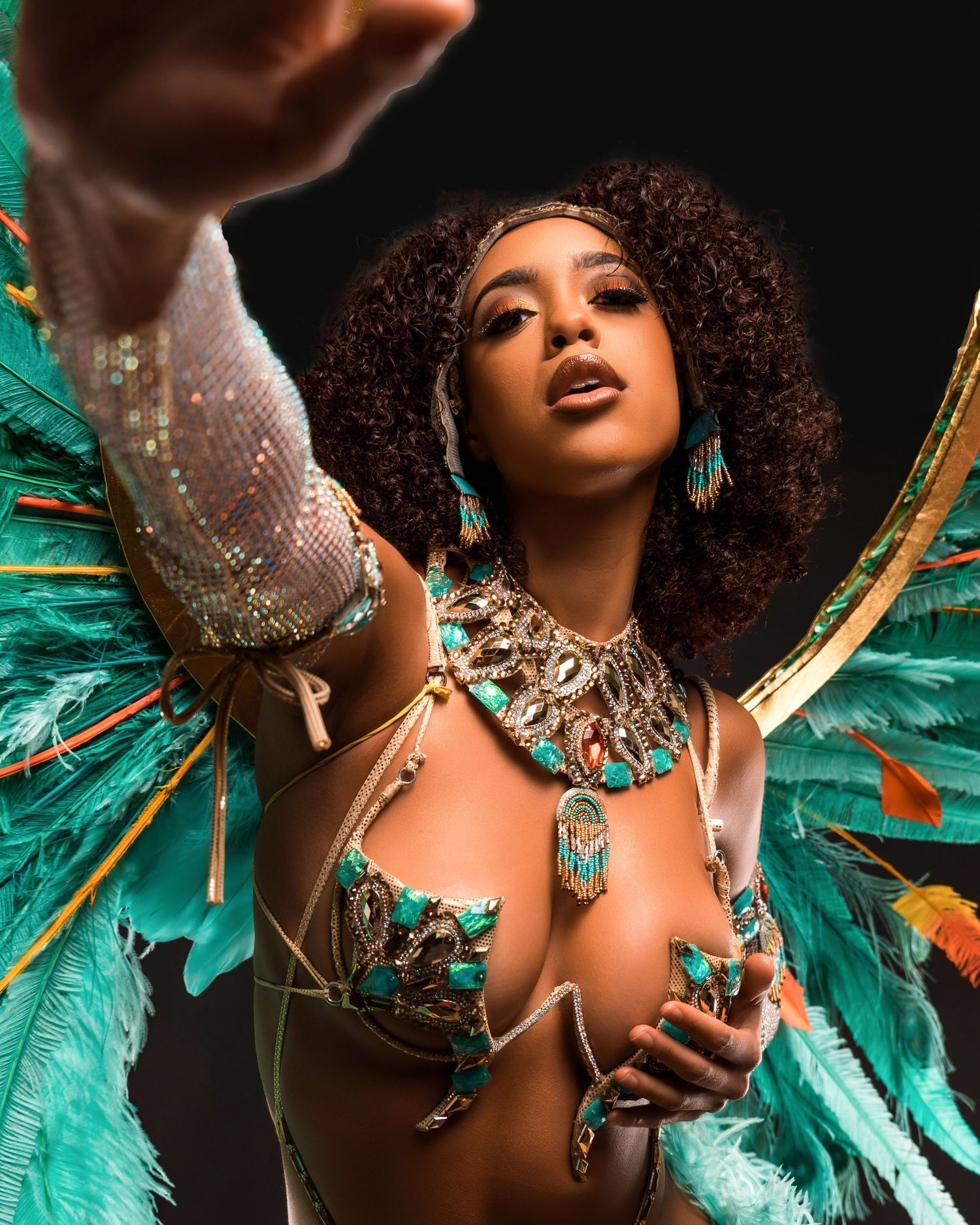Glamorous carnival costume with turquoise feathers and intricate jewelry details.