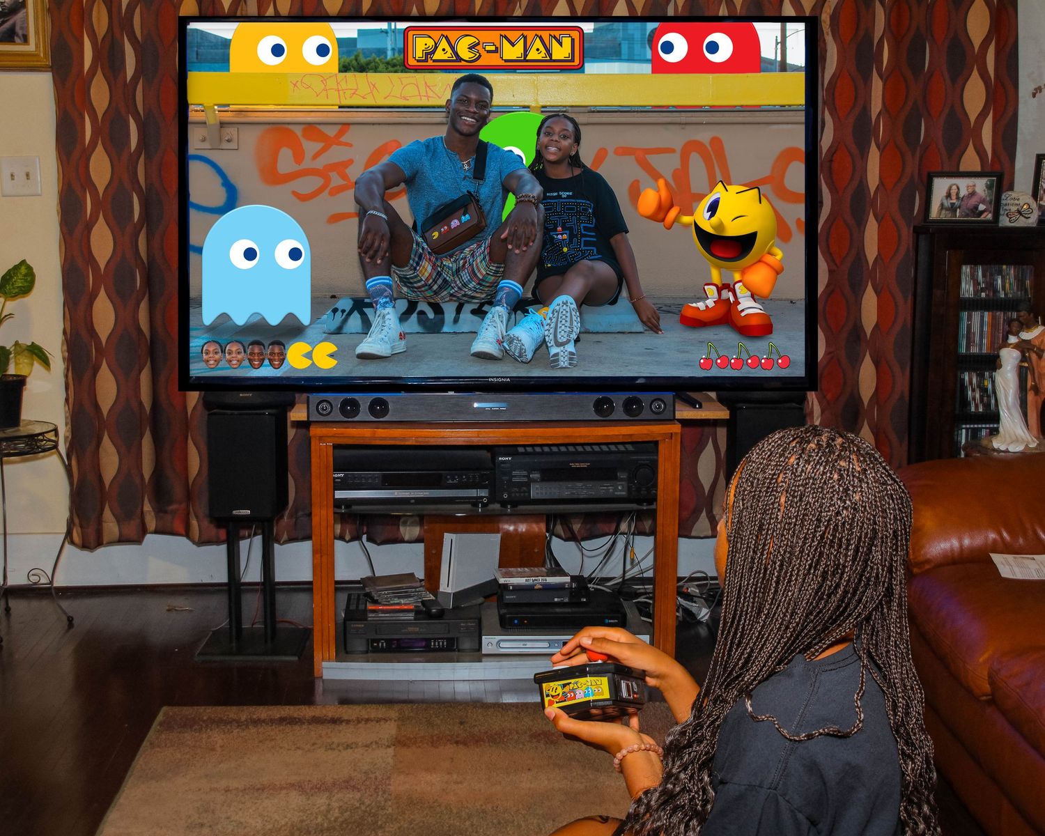 People playing Pac-Man video game on large TV screen in living room.