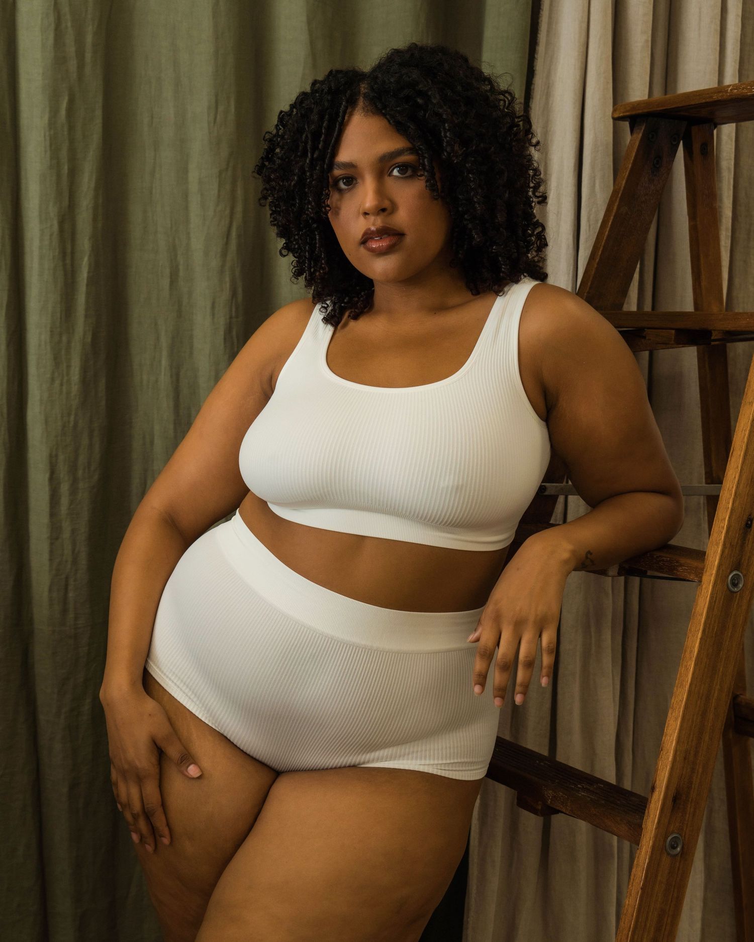 Body positive fashion shoot featuring white athletic wear in natural indoor lighting.