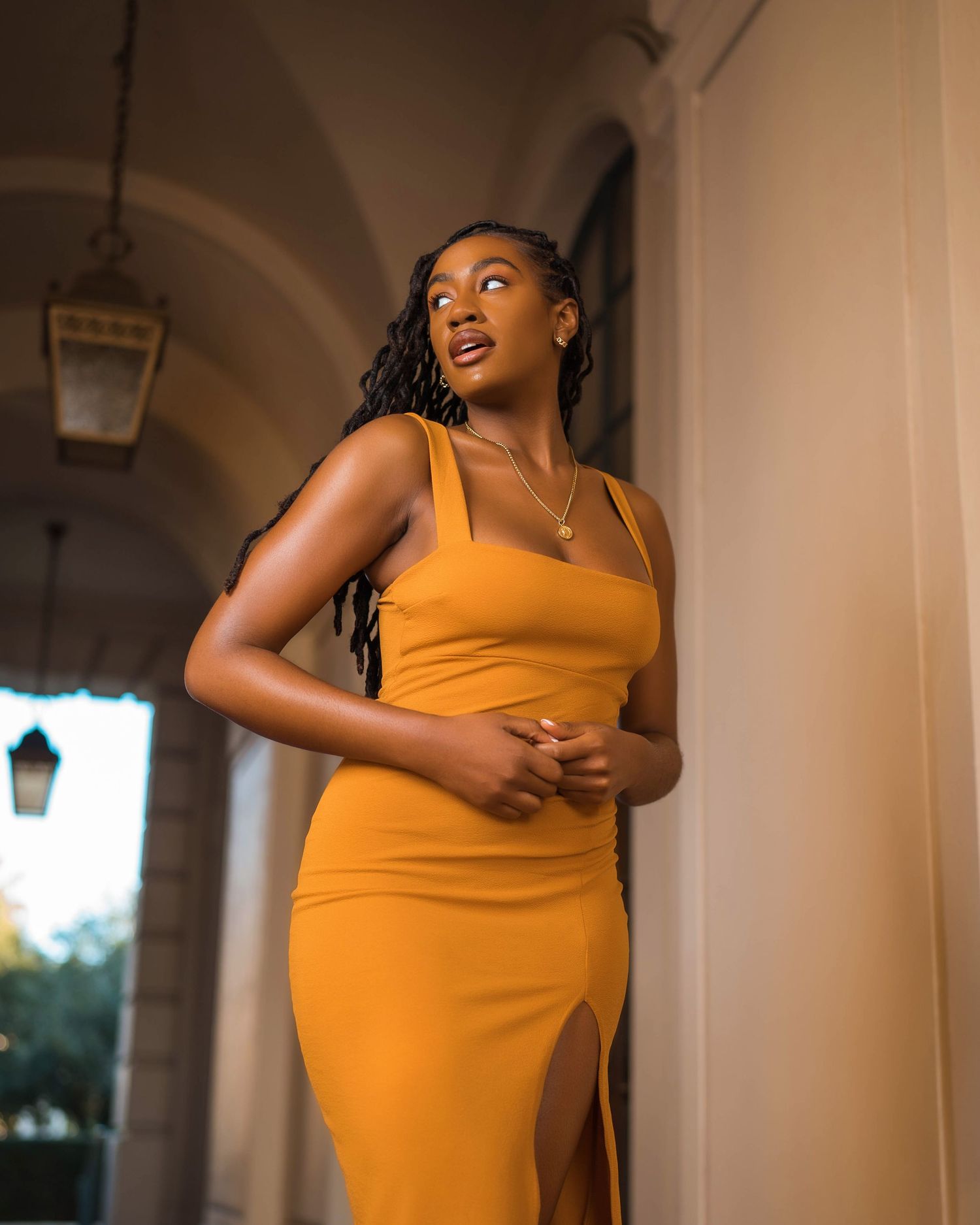 Figure in yellow dress strikes dynamic poses against interior archways.