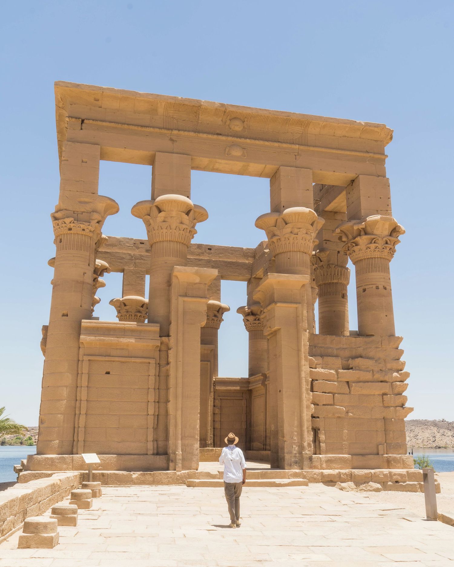 Ancient Egyptian temple ruins with ornate columns and archways in golden sandstone against a bright blue sky.