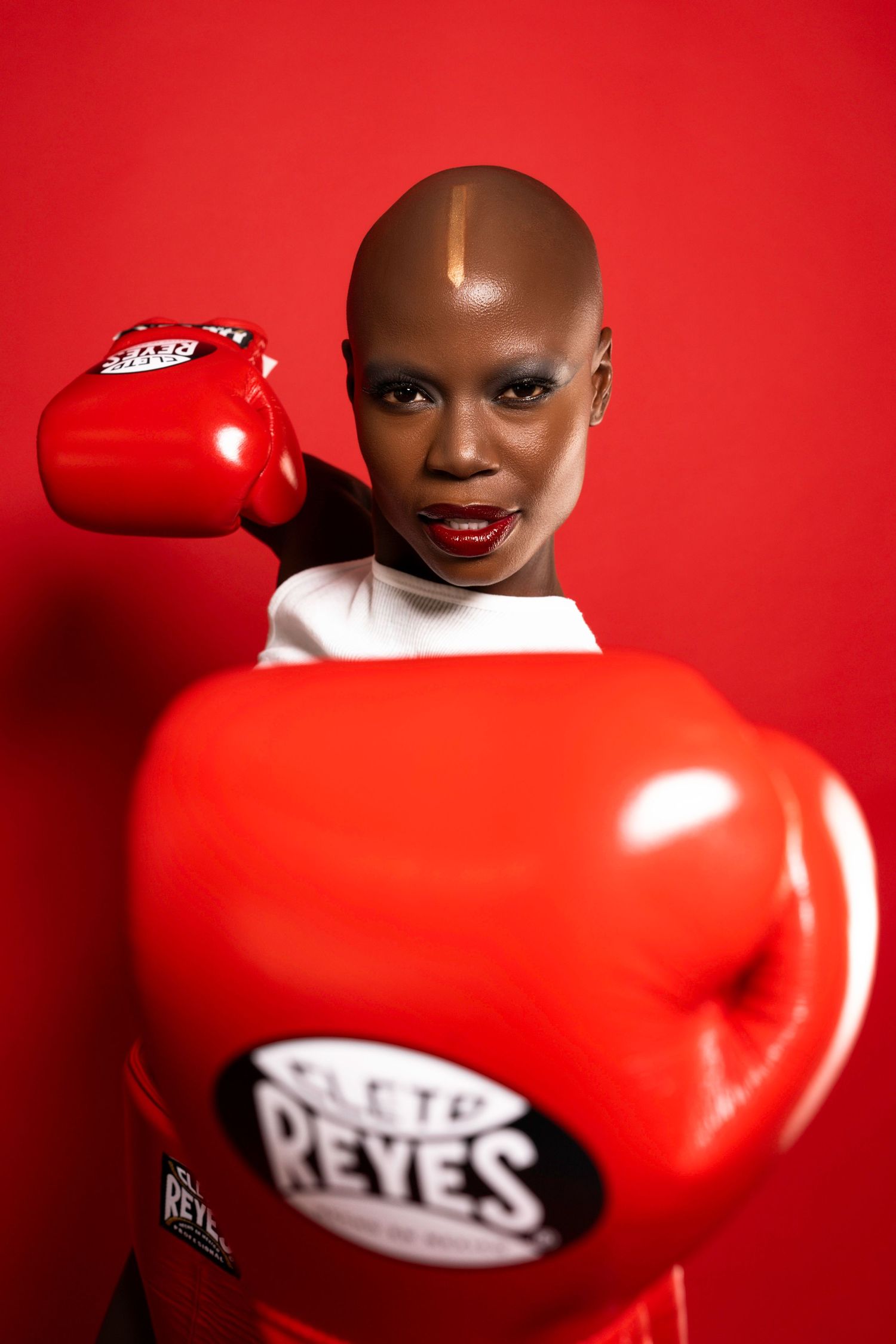 Dramatic boxing glove shot against red background in fashion editorial style.
