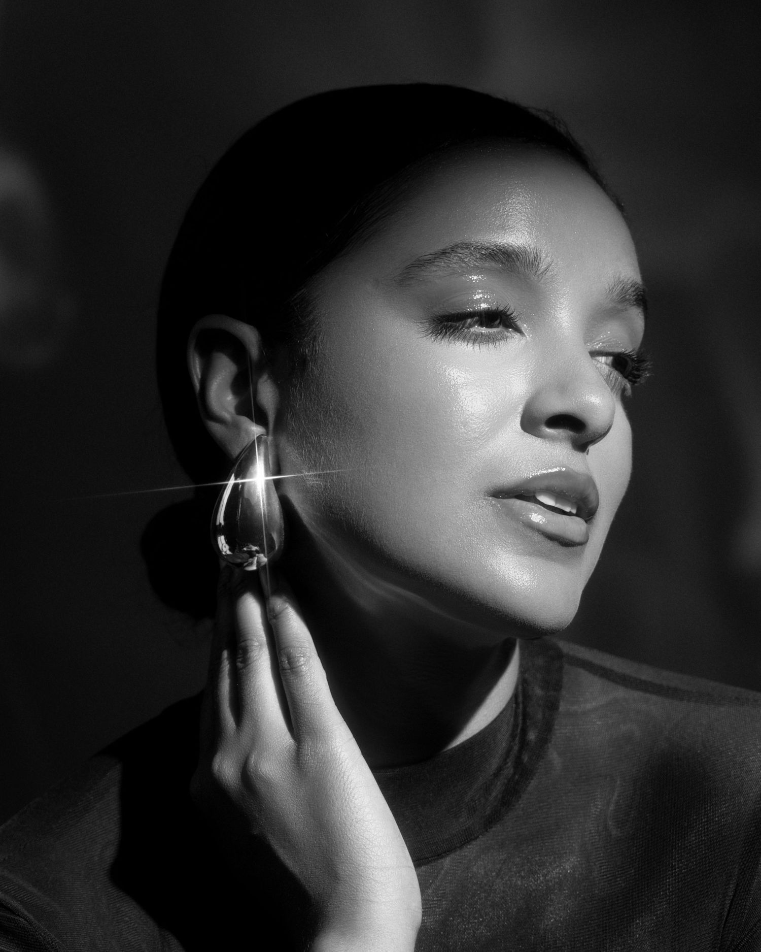Artistic black and white portrait with dramatic shadows and geometric earring detail.