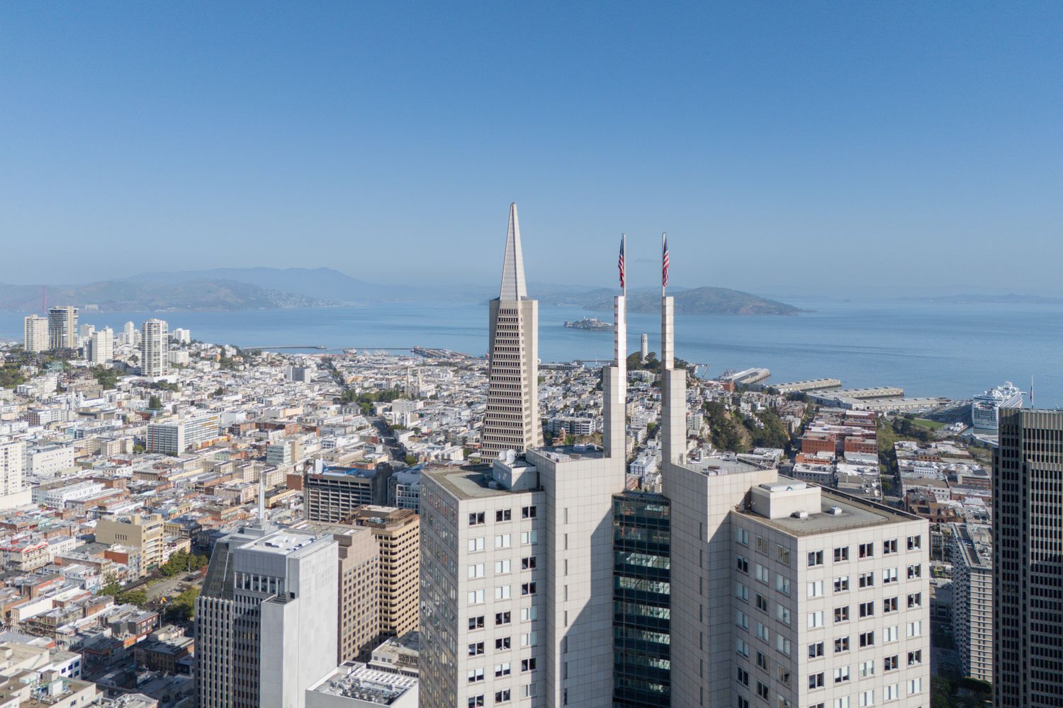 Panoramic cityscape view of modern buildings and skyscrapers against clear blue sky.