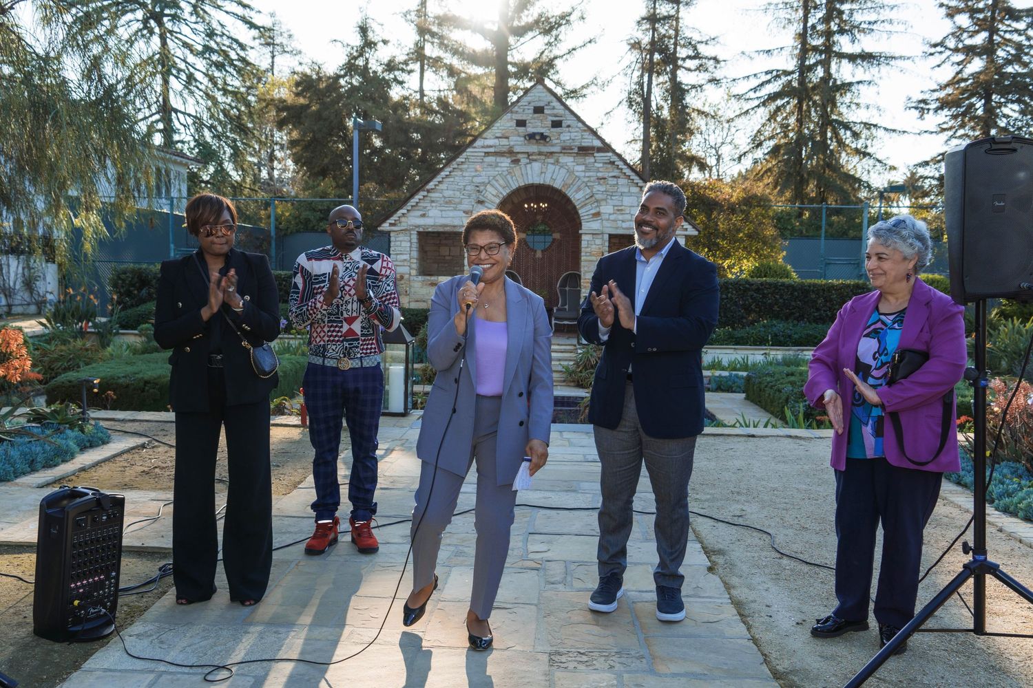 Group of performers singing outdoors in front of a small chapel.