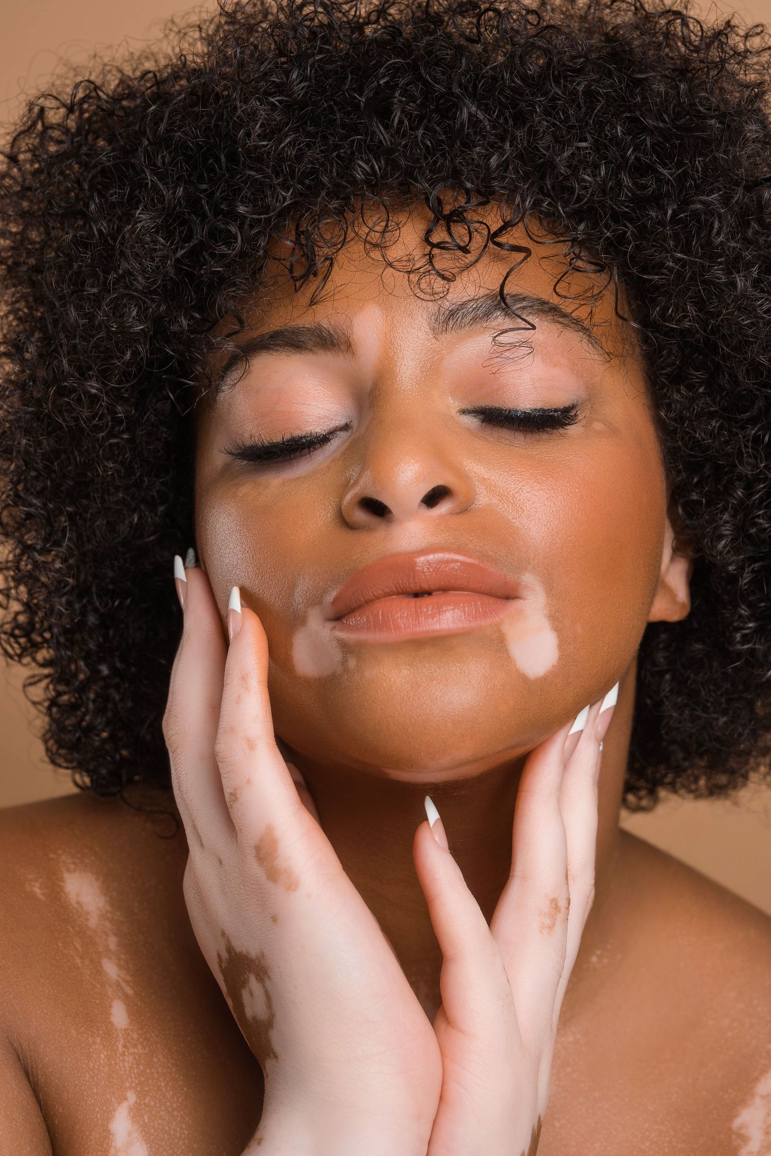 Artistic portraits showing gentle hand poses and natural curly hair against warm lighting.