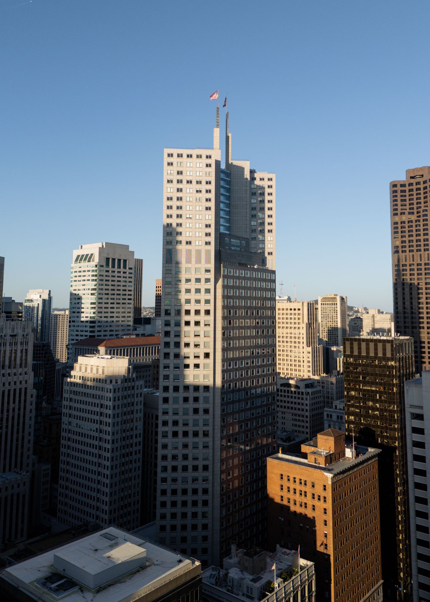 Modern downtown cityscape with tall office buildings and skyscrapers against a clear blue sky.