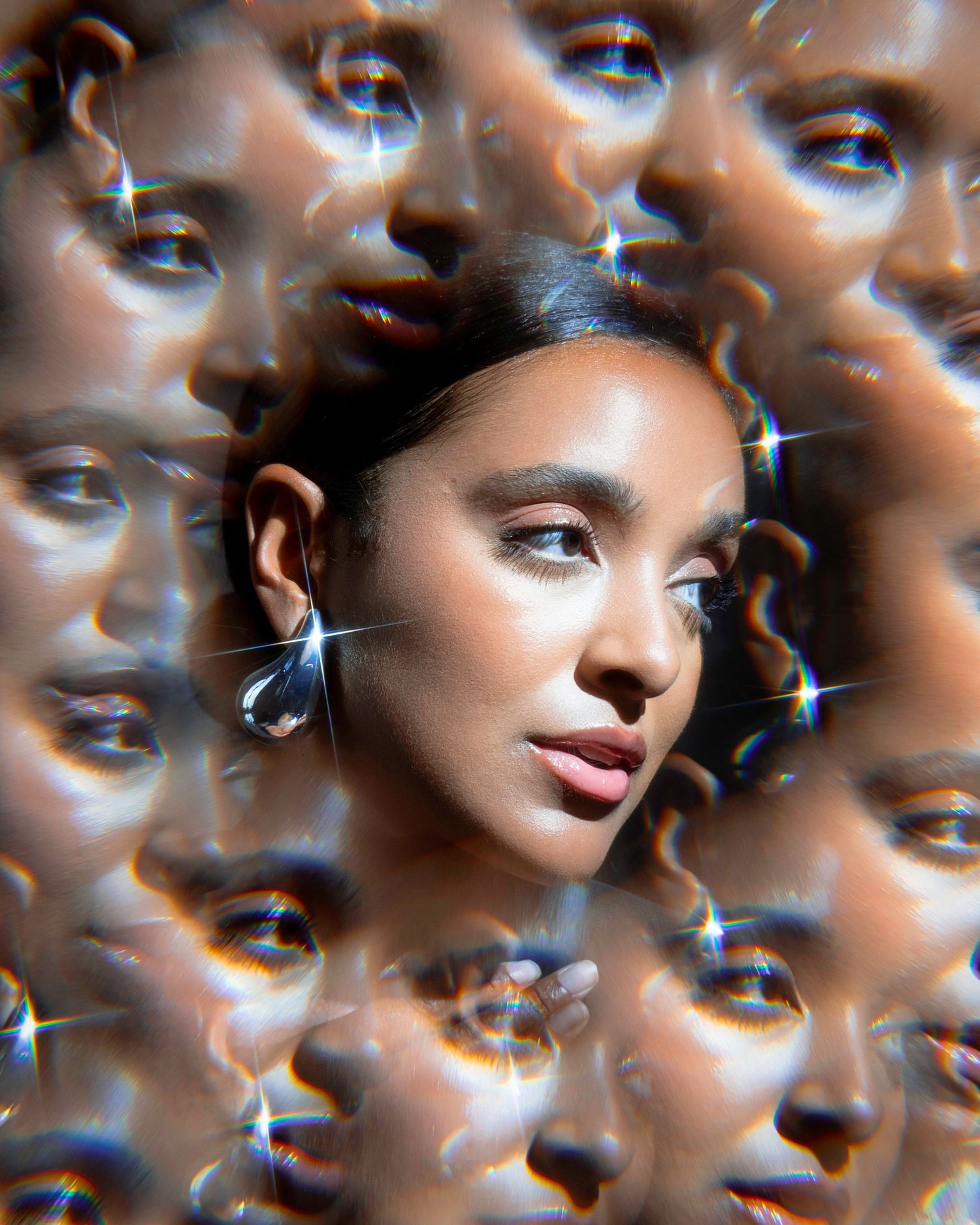 Artistic beauty portrait with kaleidoscope effect showing multiple reflections and crystal earrings.