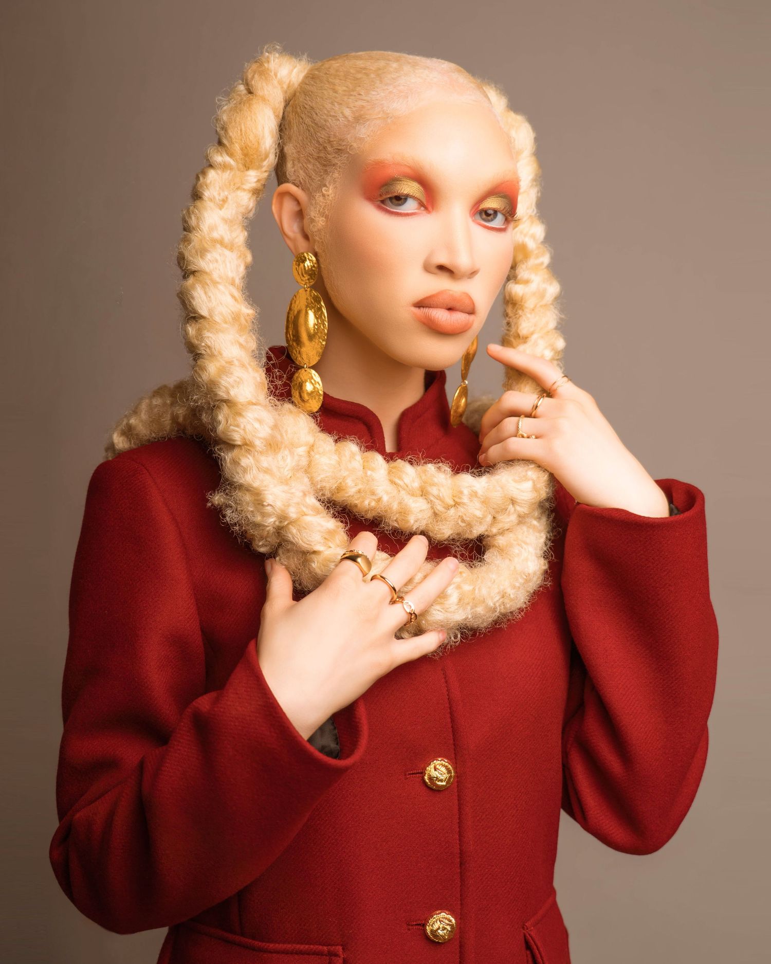 Fashion portrait series featuring a model in a red coat with blonde braided hair.