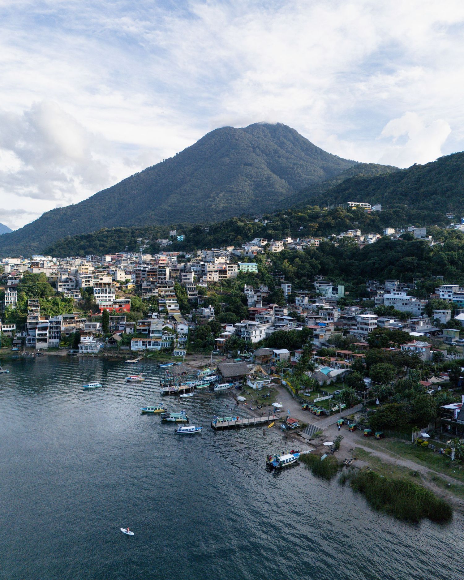 Aerial view of a lakeside town with boats and docks nestled against mountainous terrain.