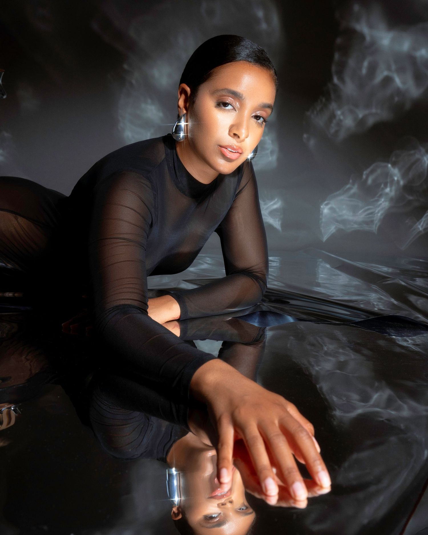 Fashion portrait with sheer black top and dramatic smoke effects in moody lighting.
