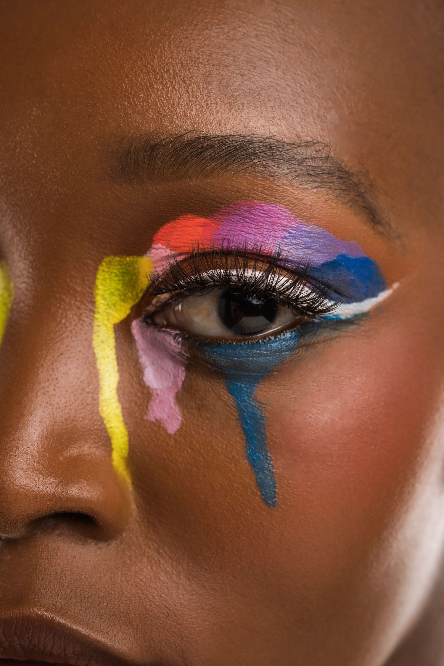 Macro shots of avant-garde eye makeup featuring multicolored abstract paint strokes and white liner.