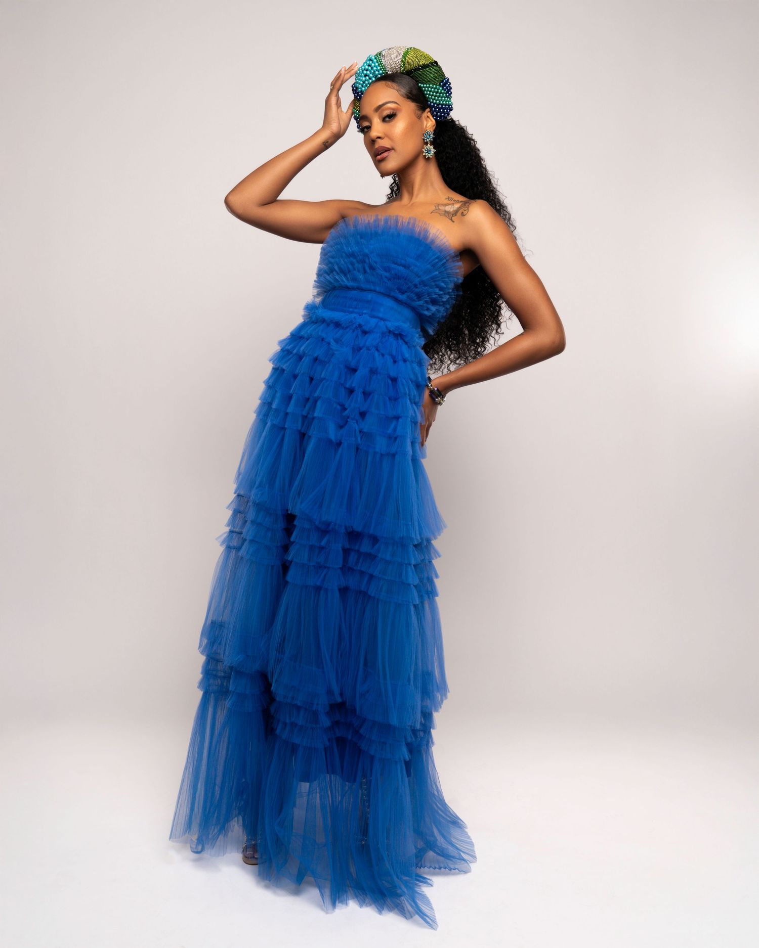 Royal blue tulle layered dress with teal hair accessory against white background.