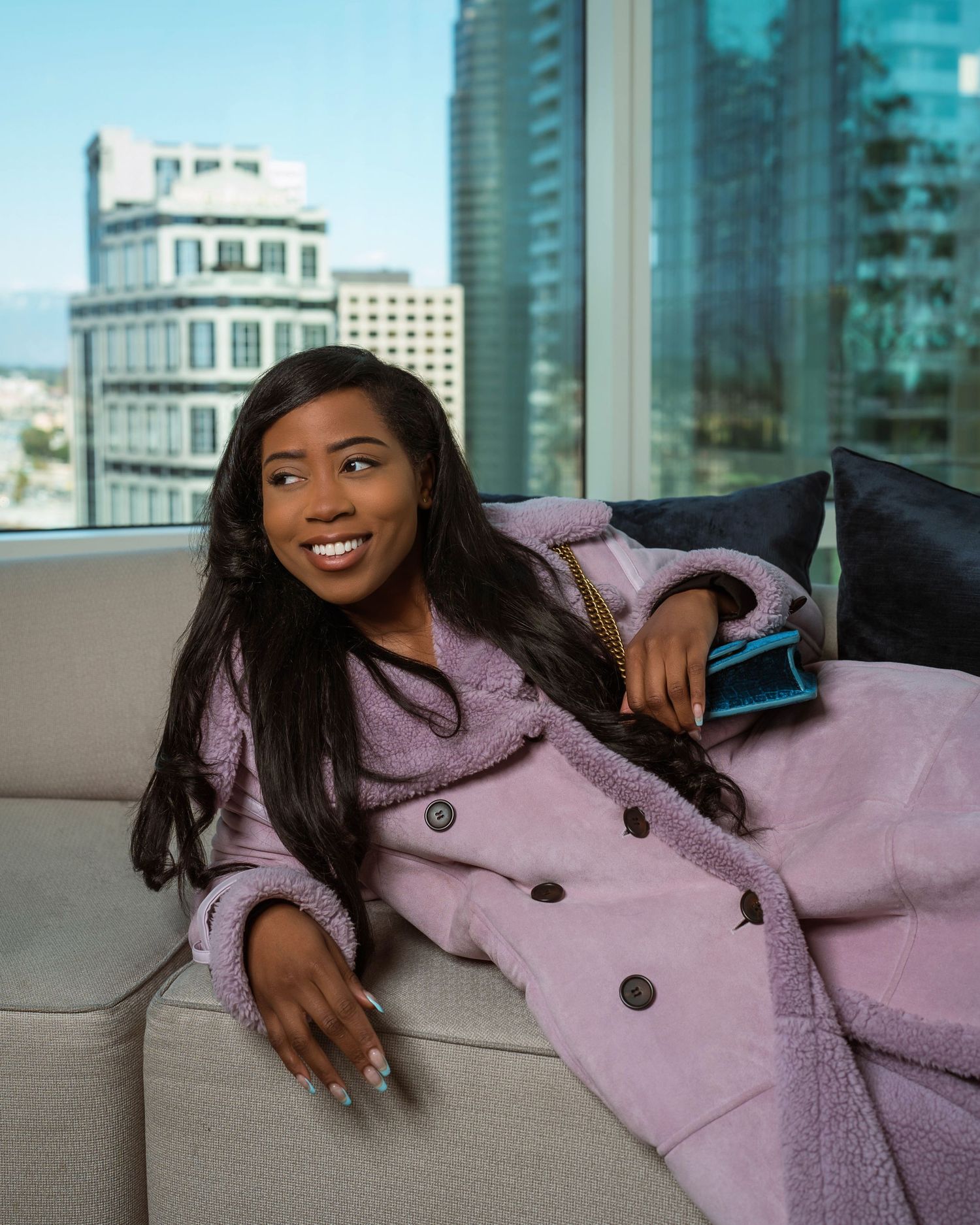 Fashion photography session with pink winter coat in modern high-rise setting.